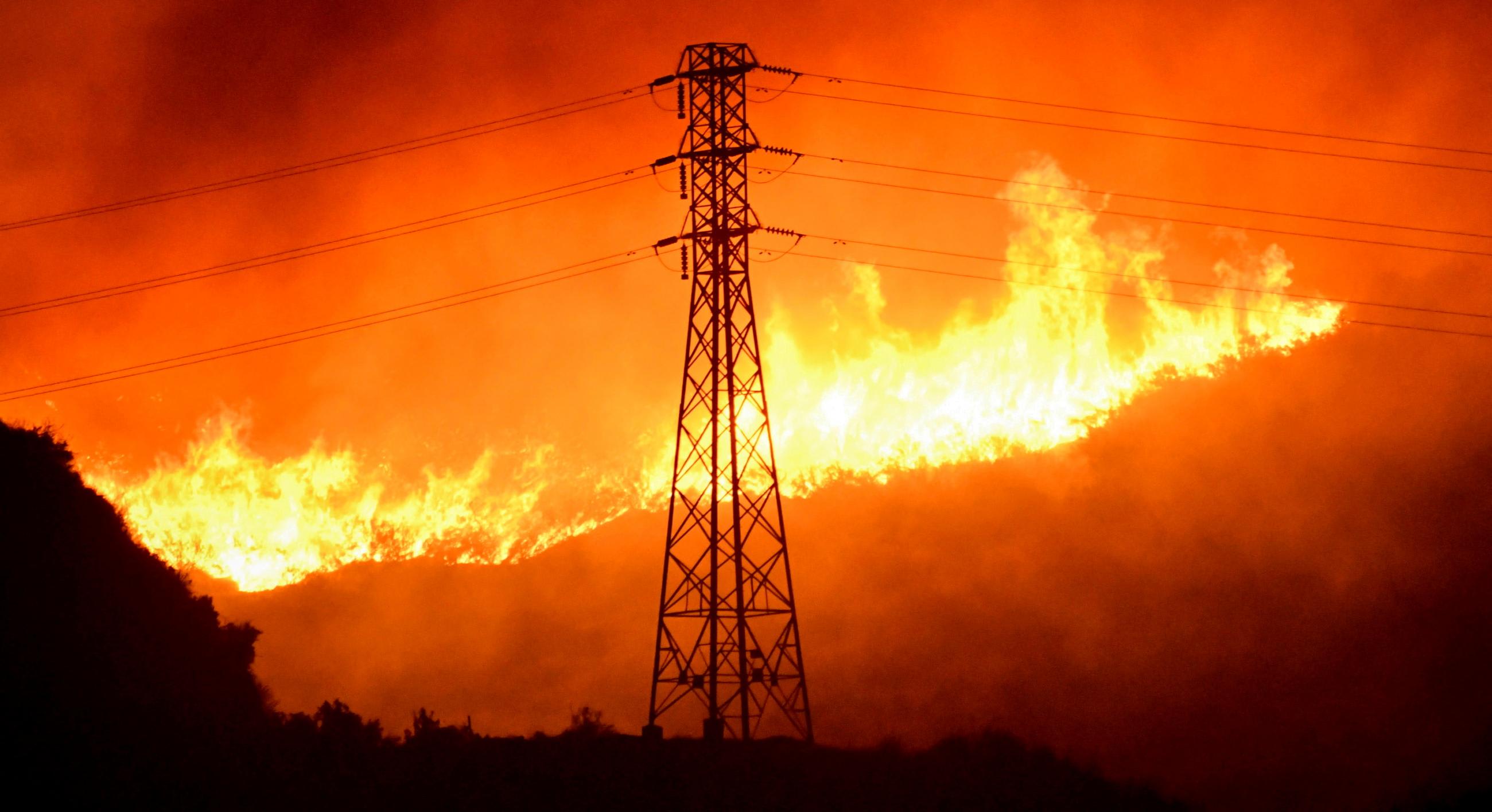 A wind-driven wildfire burns near a power line tower in Sylmar, California, on October 10, 2019.