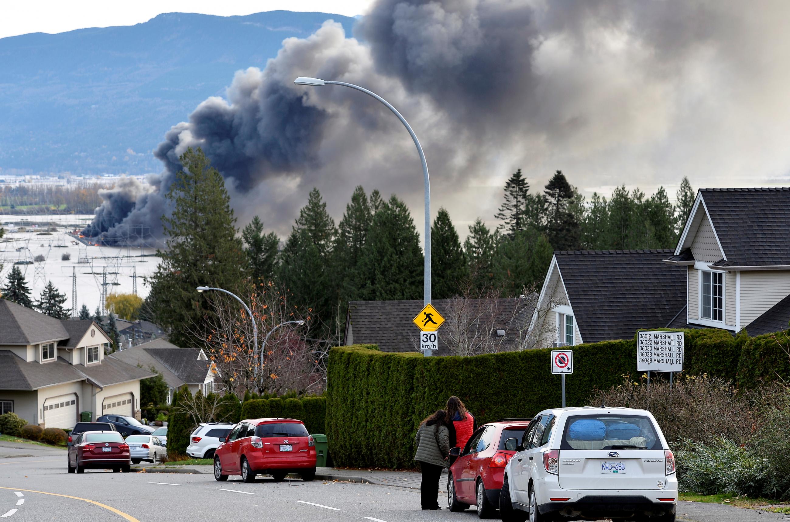 People watch as a fire burns at a storage lot for RVs days after rainstorms lashed the western Canadian province of British Columbia, triggering landslides and floods, and shutting highways, in Abbotsford, British Columbia, on November 17, 2021.