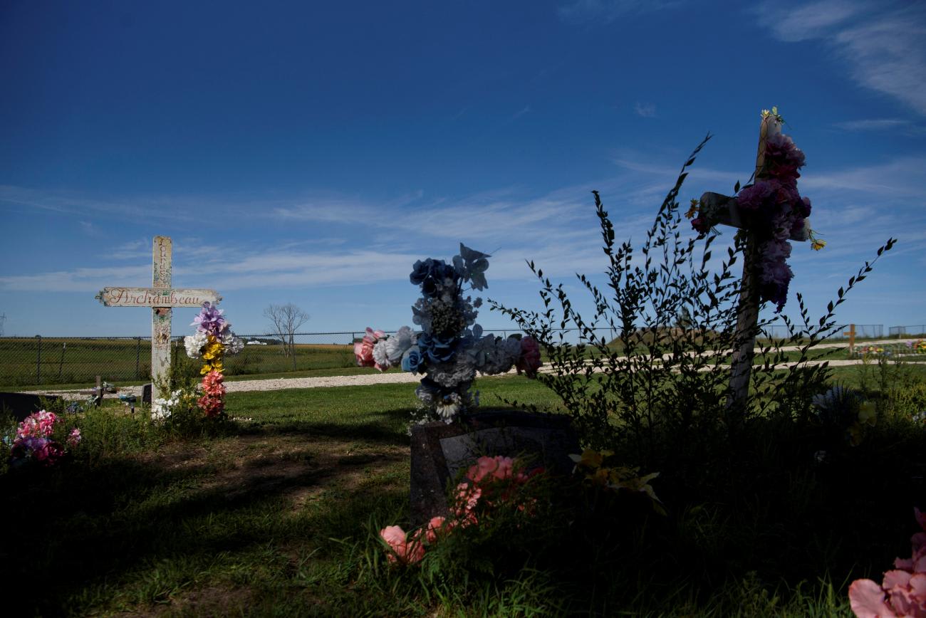 A deep blue sky stretches above a graveyard with large crosses adorned with flowers at St. Paul's Catholic Church on the Yankton Indian Reservation in Marty, South Dakota, on September 8, 2021.