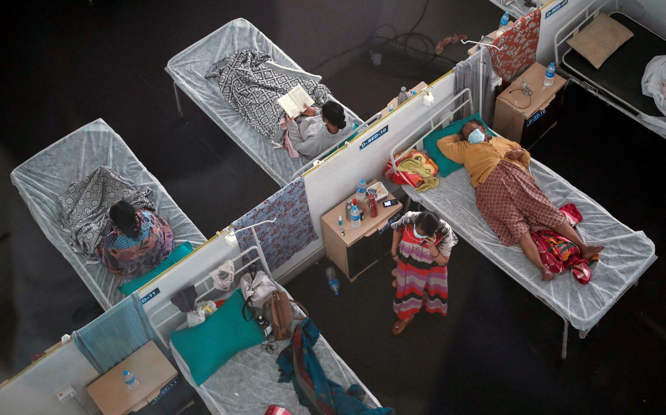 A bird's eye view of three women on cots and one standing inside a quarantine center for COVID-19 patients, in Navi Mumbai, India, on January 11, 2022.