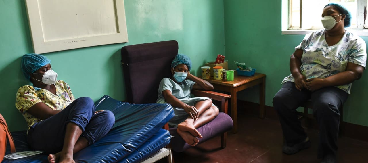 Three exhausted health workers rest on chairs and a couch during the January 2021 surge of COVID-19 at Queen Elizabeth Central Hospital in Blantyre, Malawi.