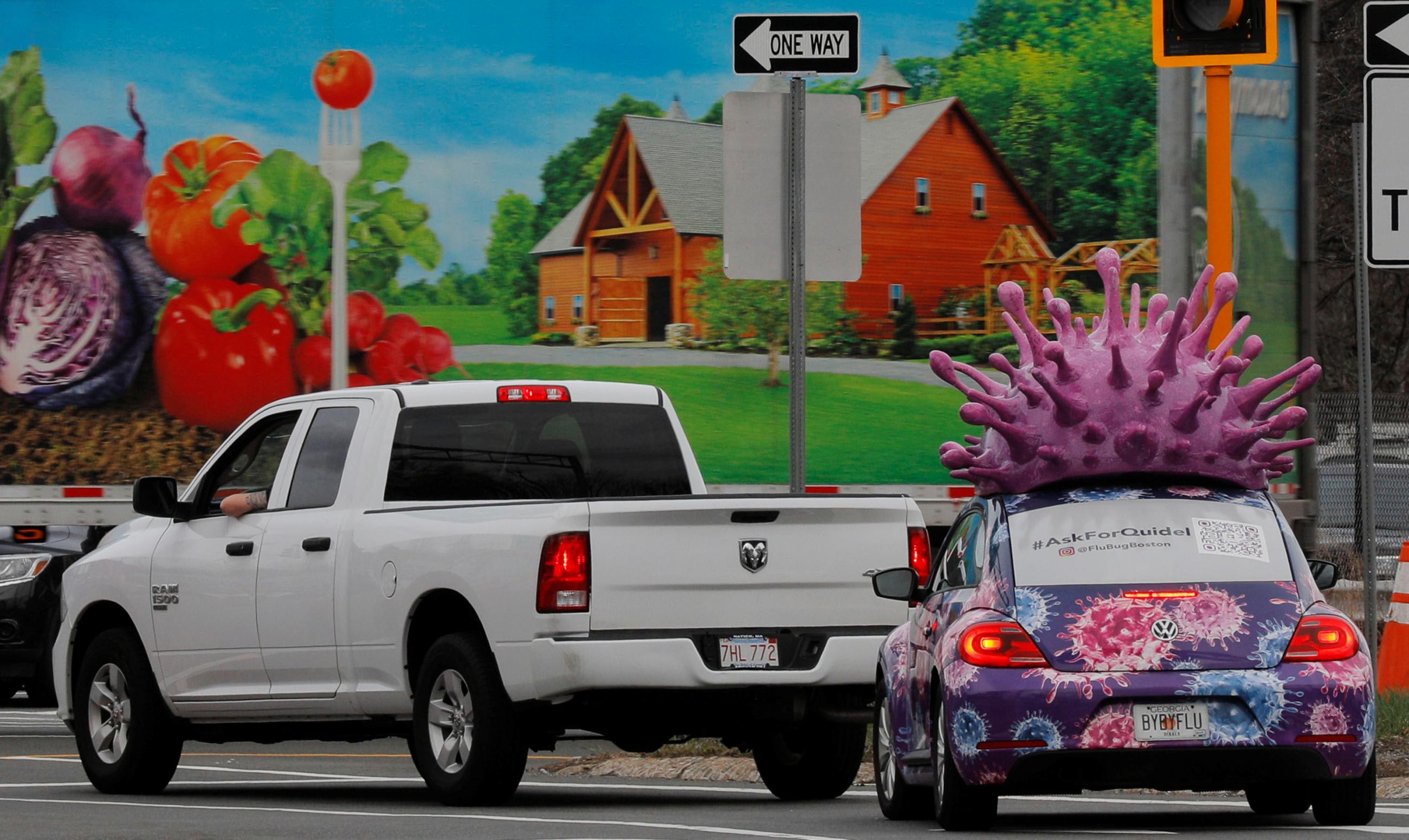 A colorful car advertising test kits for the flu and the coronavirus disease waits at a traffic light. It has a large purple model of an influenza virus on its roof, in Medford, Massachusetts, on March 31, 2021. REUTERS/Brian Snyder