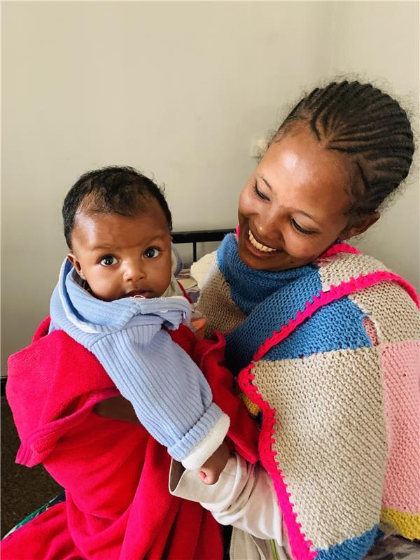 A woman holds her child as many women like Nigisty are now reclaiming their right to safe births in the aftermath of the war.