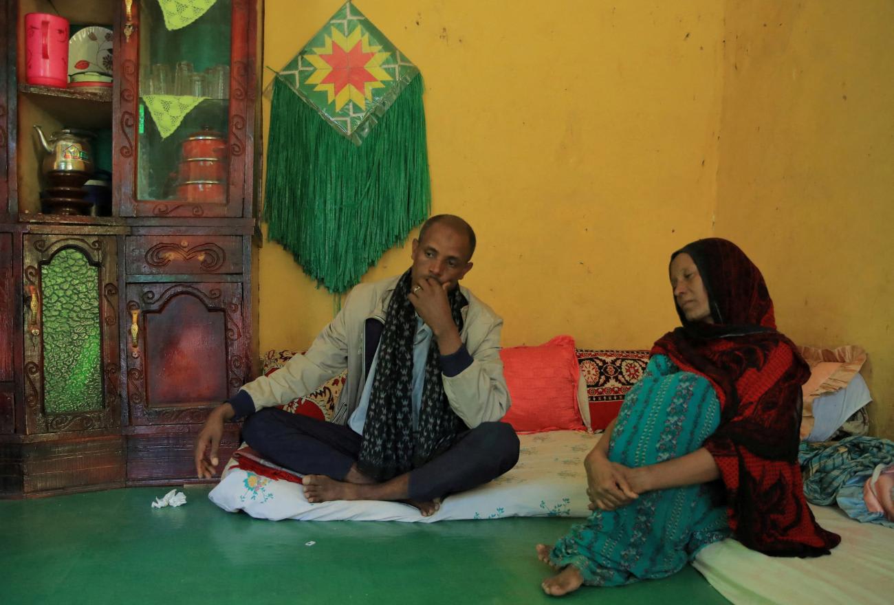 Jemal Abdella and his wife Tirungo Ambaye sit on a green floor in a room with yellow walls. They are mourning the loss of their daughter Zara, 17, who was killed by Tigray People's Liberation Front forces for resisting rape. Photo taken near Lalibela town, Ethiopia, January 26, 2022.