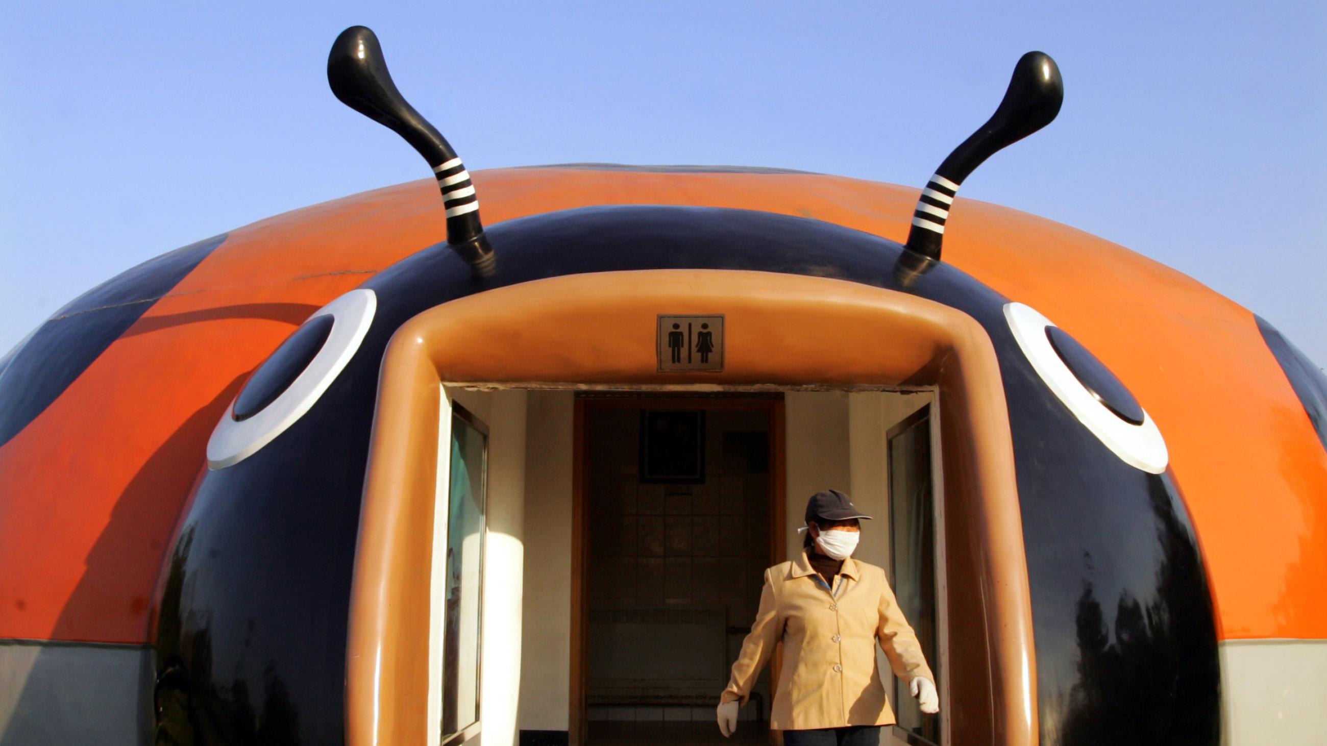 A bathroom attendant emerges from a beetle-shaped toilet at a park in Beijing, China, on November 17, 2004.