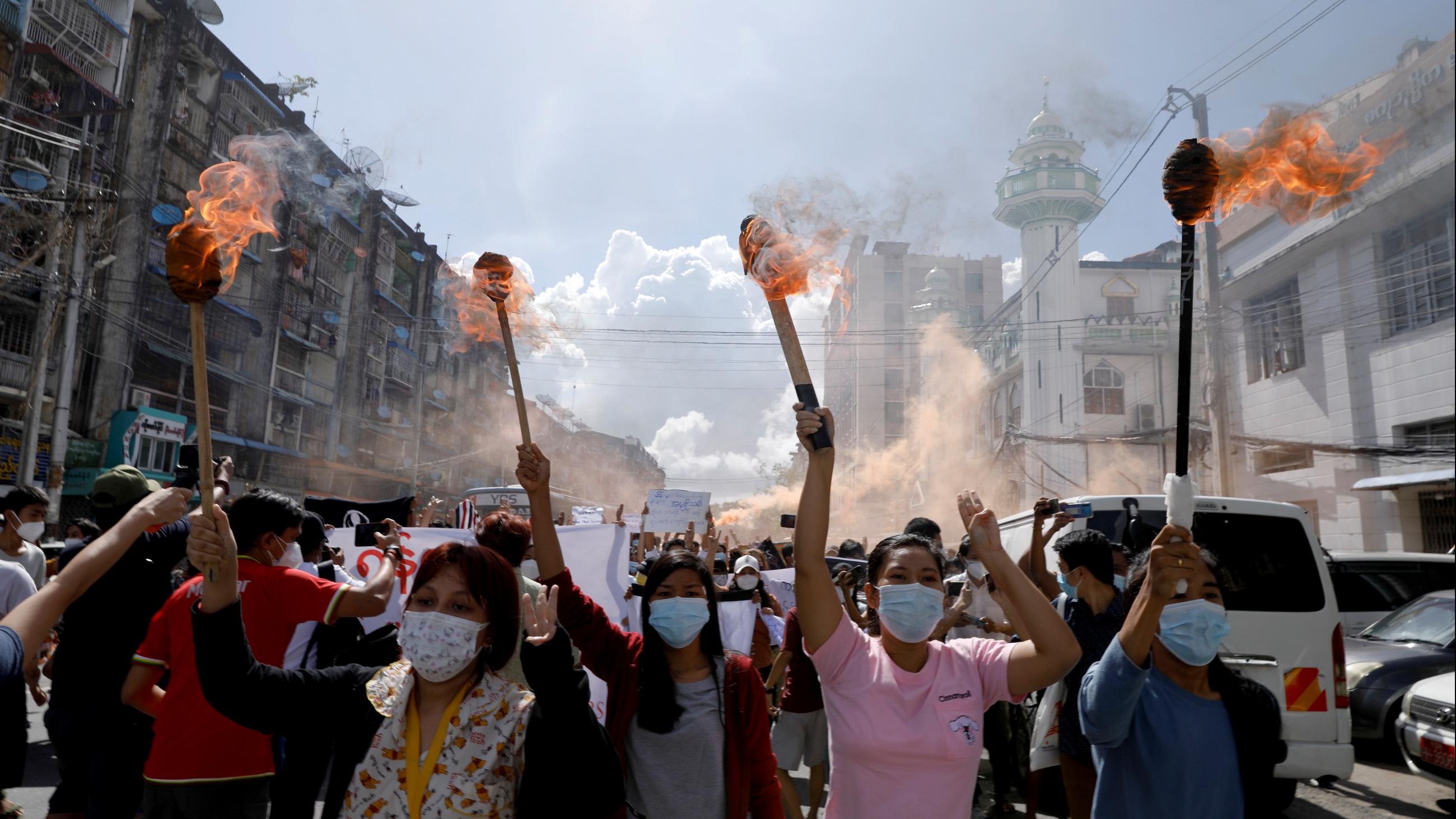 a group of women hold torches to protest the military coup in Yangon, Myanmar