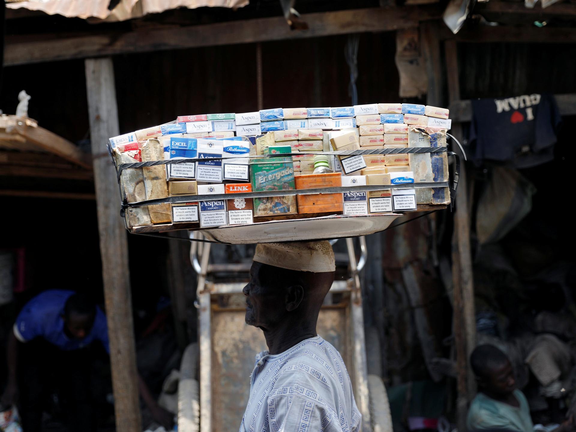 A man selling packets of cigarettes walks through a street, in the old district of Kano, Nigeria, on August 24, 2017.