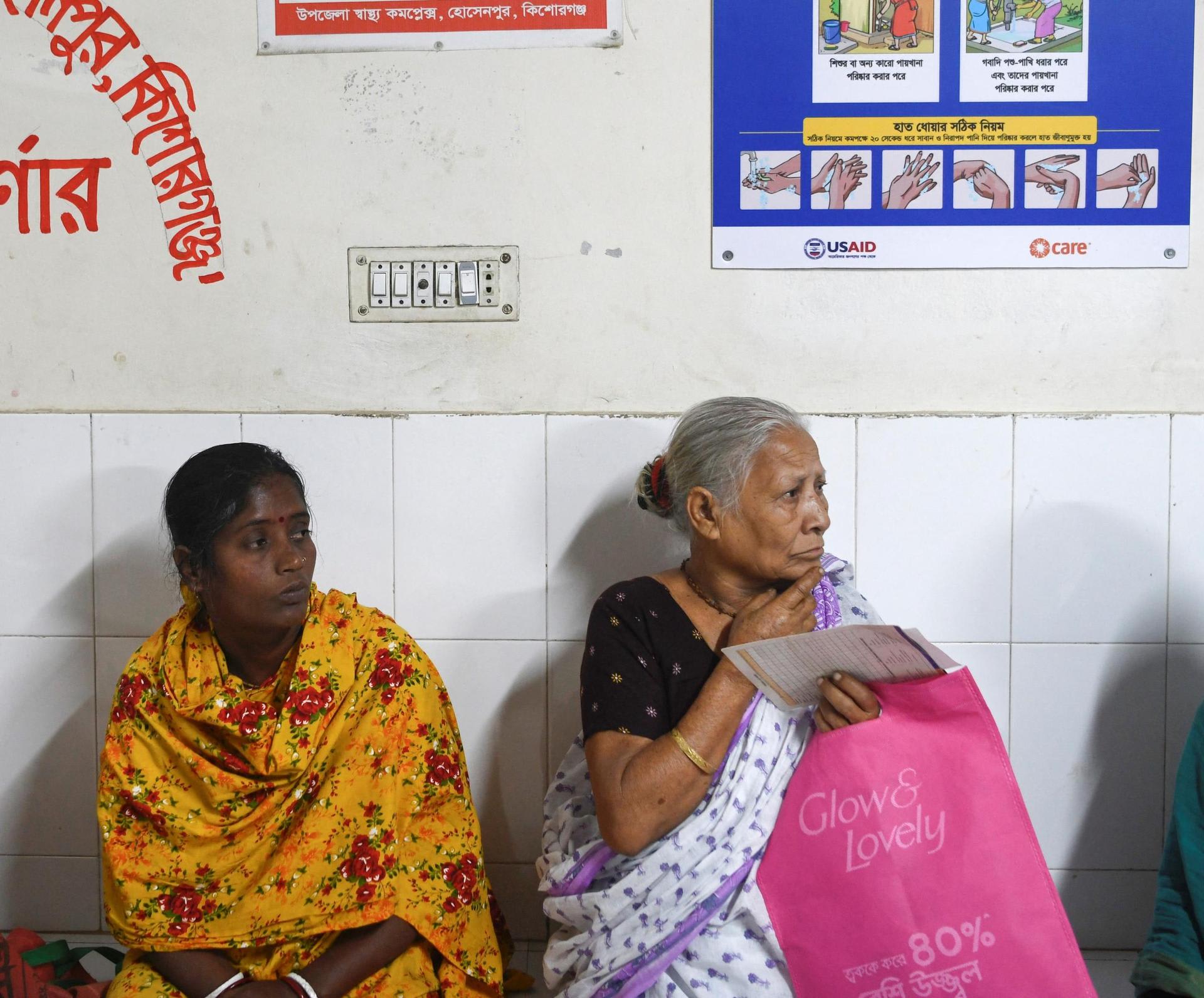 Patients wait for treatment as a USAID-funded health awareness poster hangs behind them, at the Hossainpur Upazila Health Complex, in Kishoreganj, Bangladesh, on February 10, 2025. REUTERS/Piyas Biswas