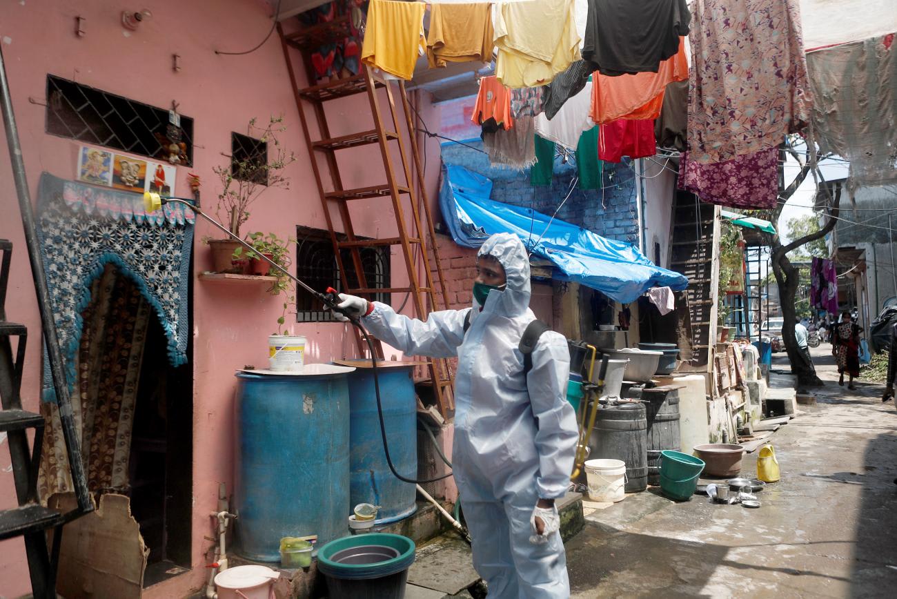 A man wearing personal protective equipment sprays disinfectant on the walls in an alley in a slum area during a lockdown to slow the spread of the coronavirus disease, in Mumbai, India on June 29, 2020.