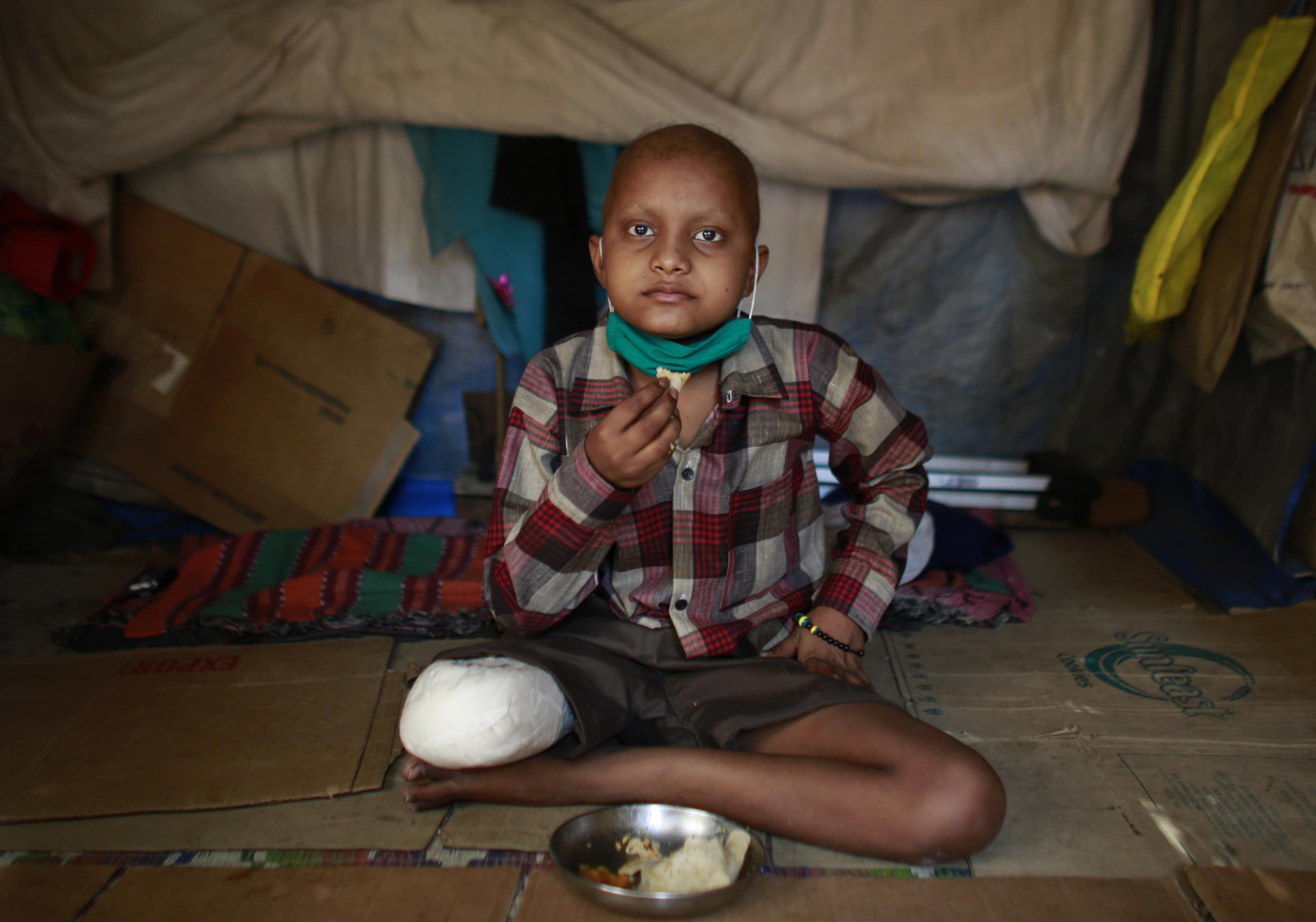 Siddharth Balasaheb, an 11-year-old cancer patient, eats his lunch as he sits inside his pavement dwelling outside the Tata Memorial Hospital.