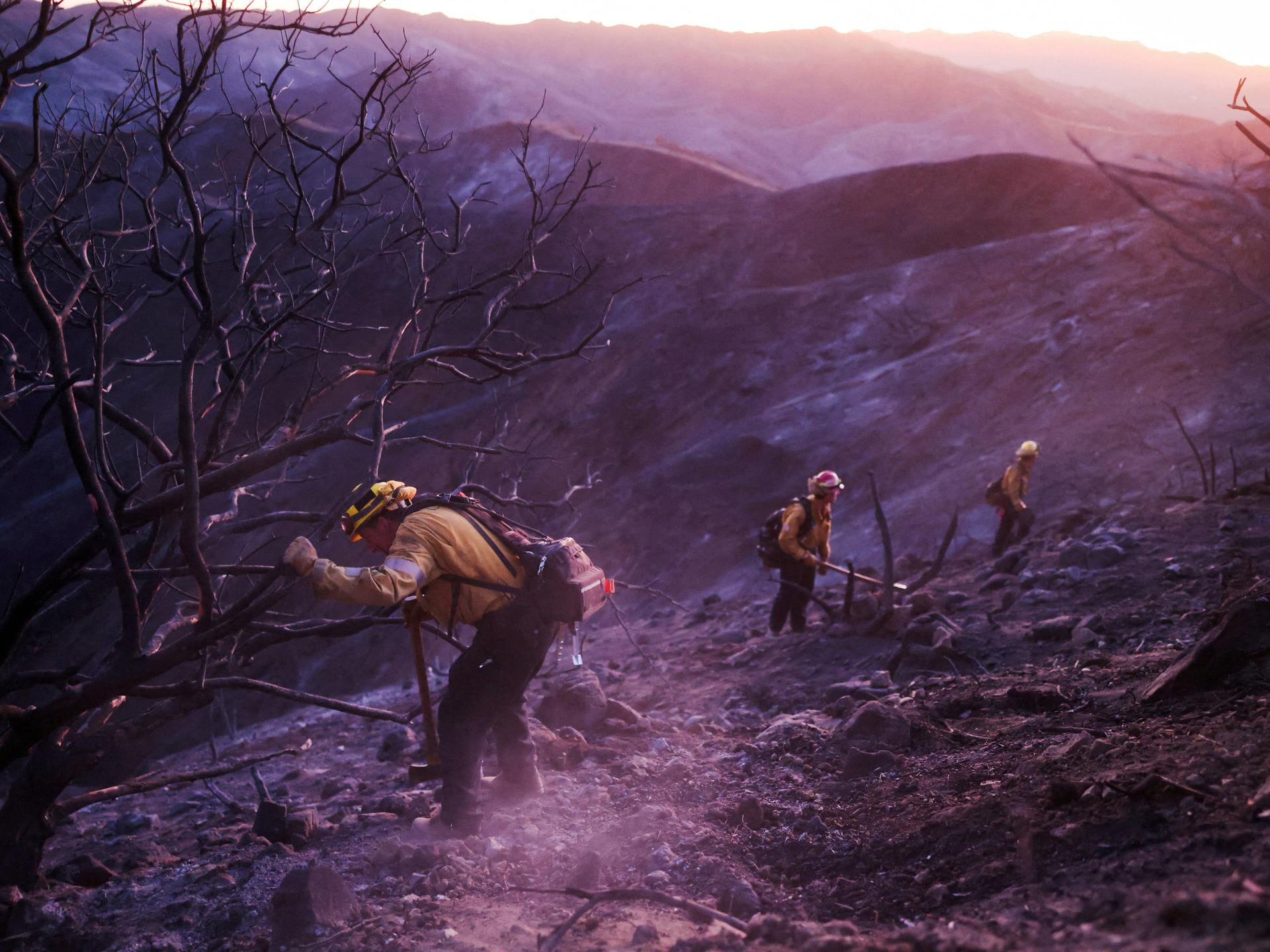 Members of a CalFire crew work to mop up hotspots from the burn scar of the Palisades Fire near Mulholland Drive, in Los Angeles, California, on January 15, 2025.