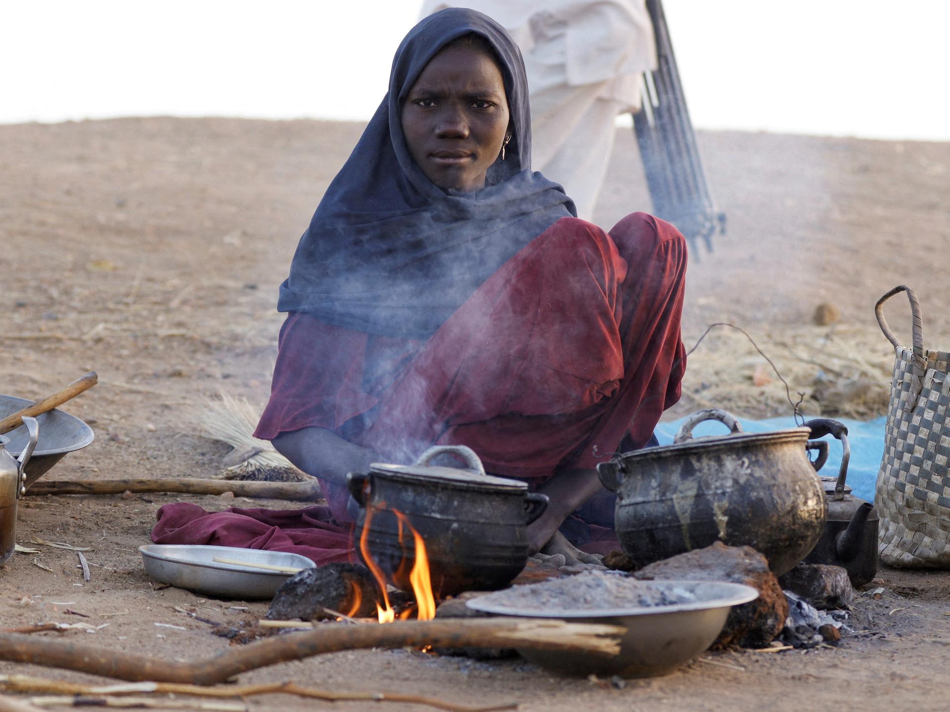 A displaced woman prepares food, following Rapid Support Forces attacks on Zamzam displacement camp, as she shelters in the town of Tawila, in North Darfur, Sudan, on April 16, 2025.