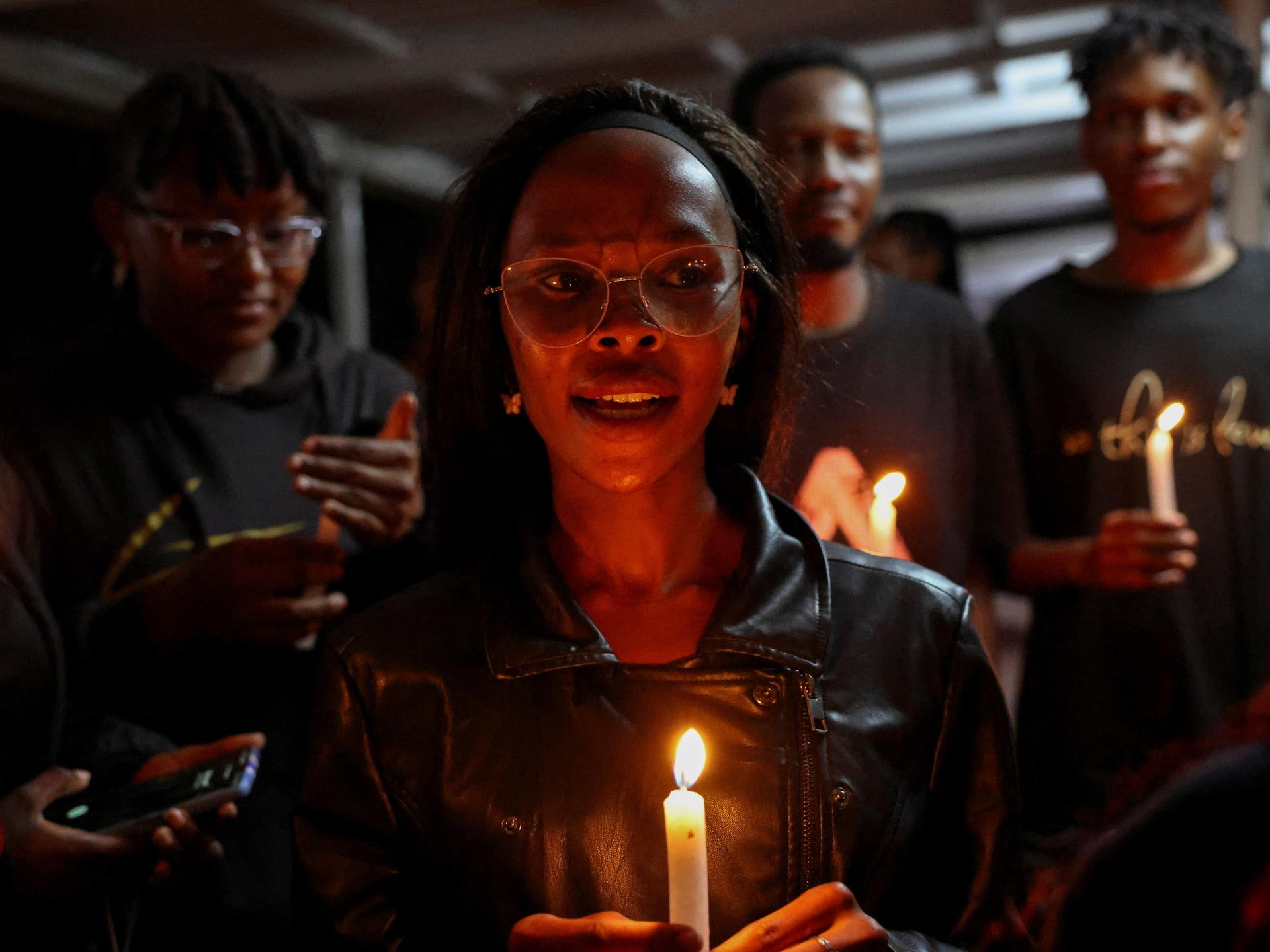 People hold candles at a vigil to raise awareness about gender-based violence and honor the lives of women lost to femicide in higher learning institutions, in Juja, Kenya, on April 11, 2025.