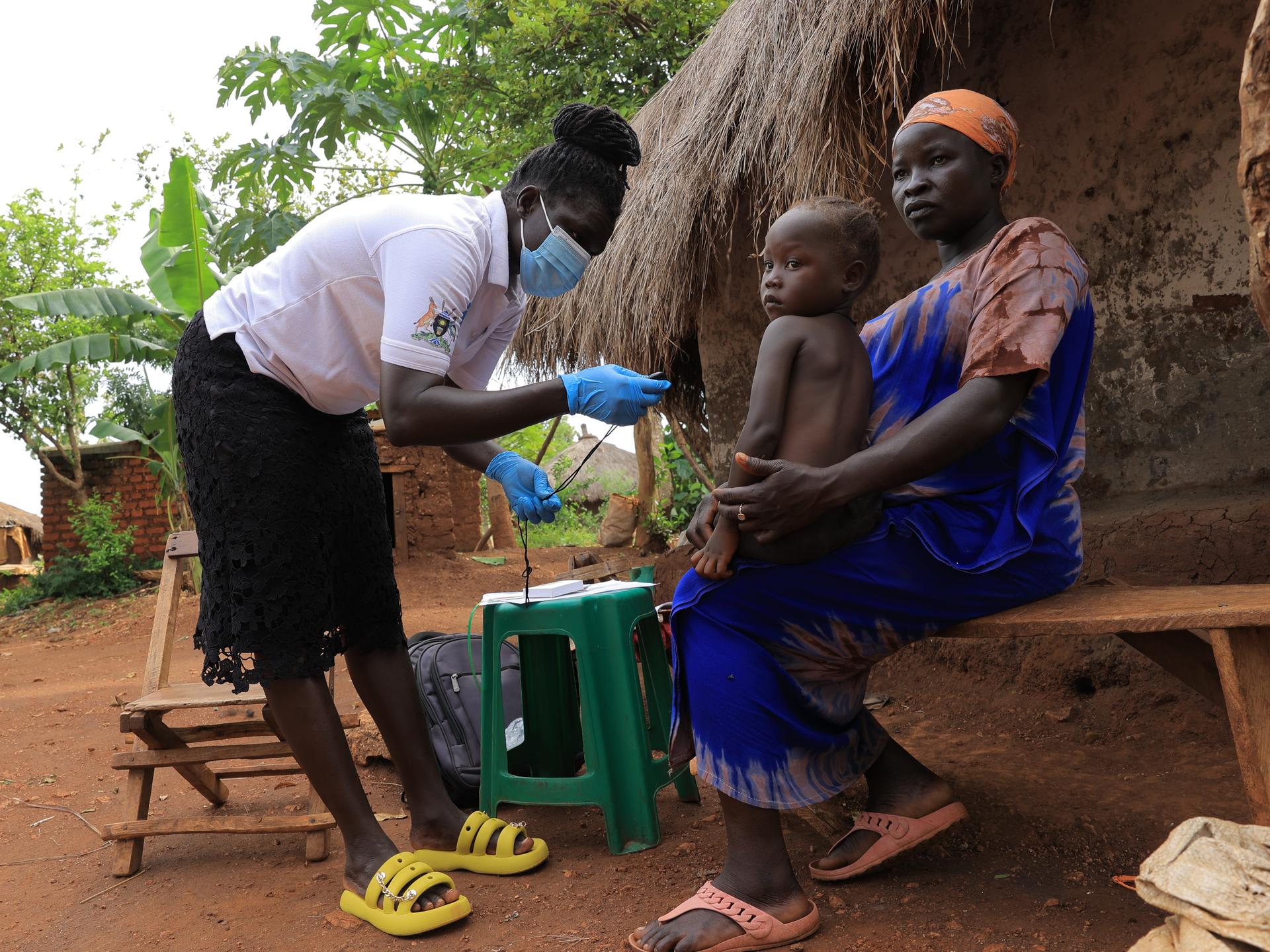 In Uganda's Bidibidi refugee settlement, a Village Health Team member conducts an in-home health visit to a refugee mother and child.