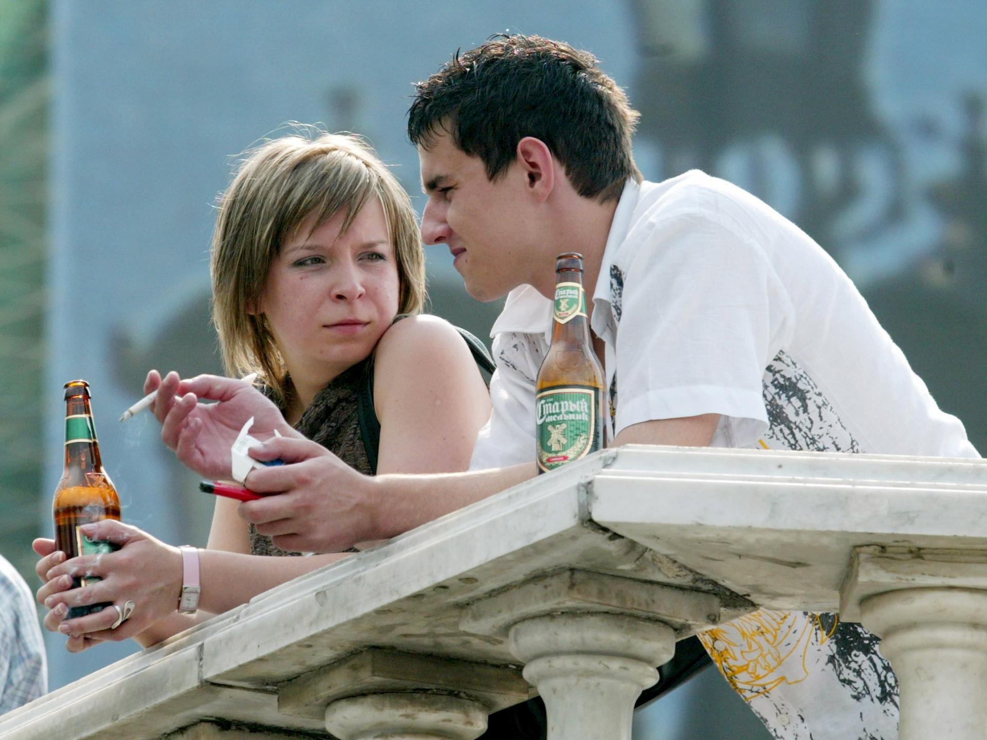 A young couple chats as they drink beer and smoke cigarettes, in Moscow, Russia, on August 8, 2004.