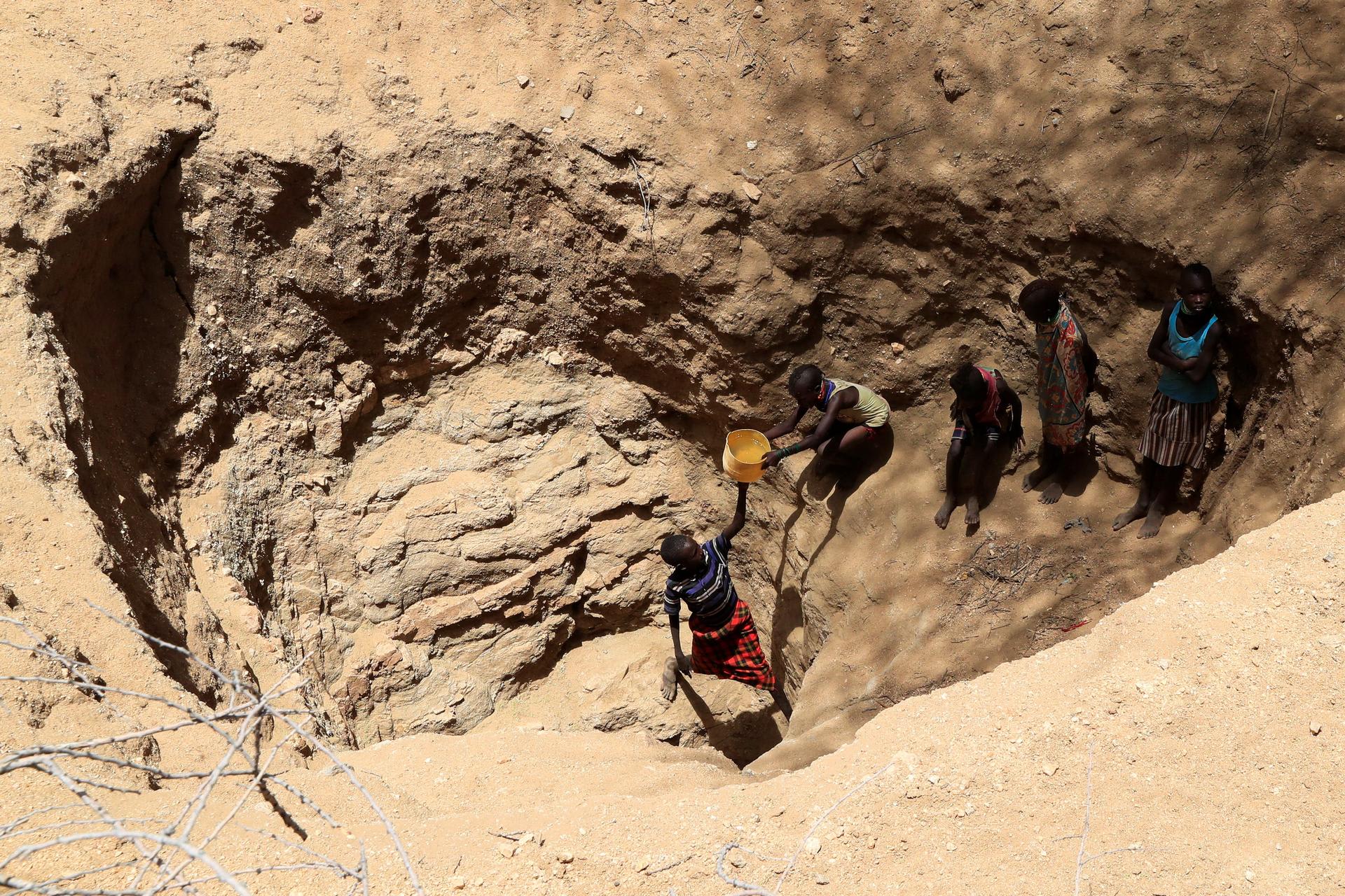 Members of the Turkana pastoralist community affected by the worsening drought due to failed rain seasons, collect water from an open well dug on a dry riverbed, Turkana, Kenya, on September 27, 2022.