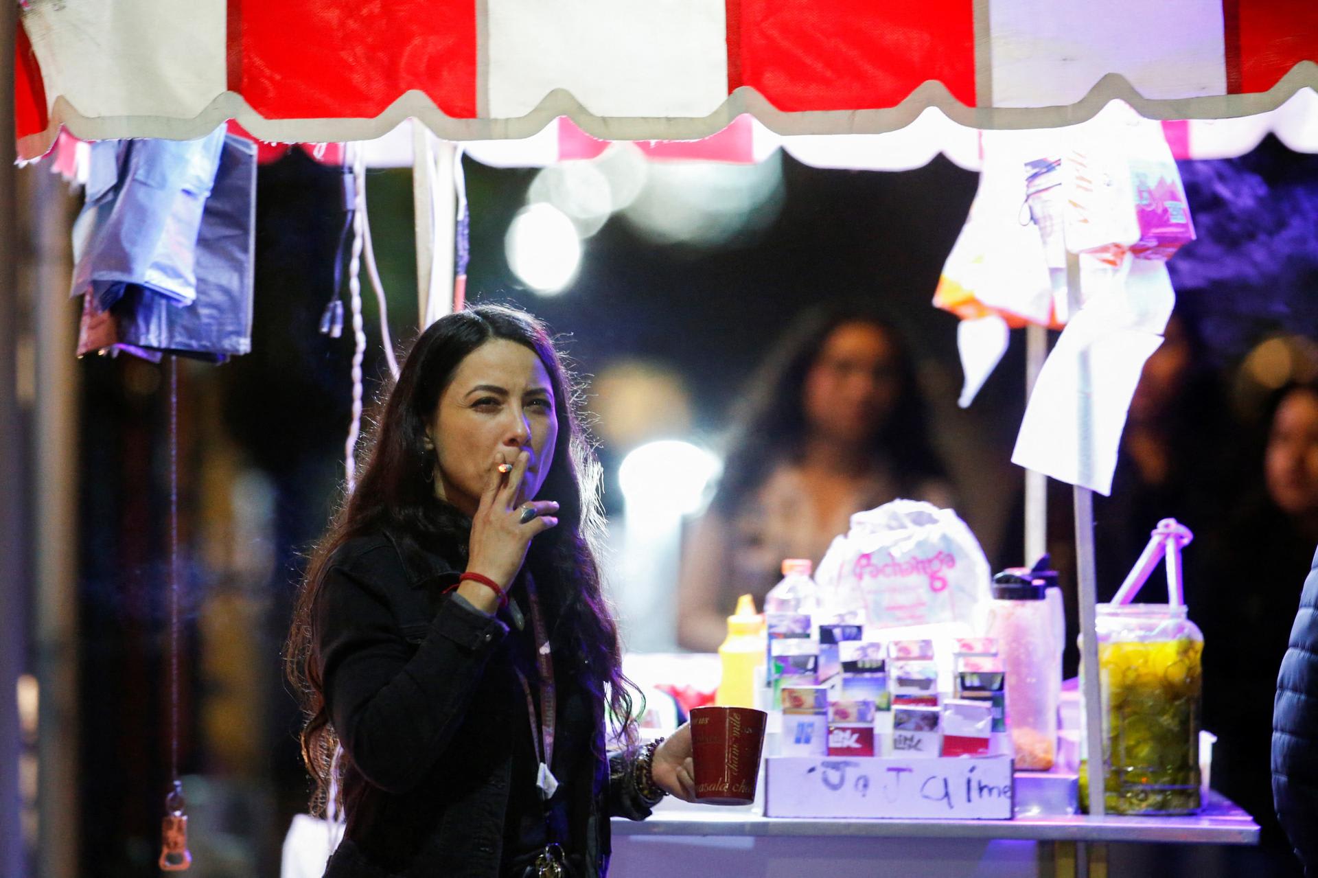 A woman smokes a cigarette next a food stall, before the Mexican government's regulation of the general law for tobacco control, in Monterrey, Mexico, on January 14, 2023.