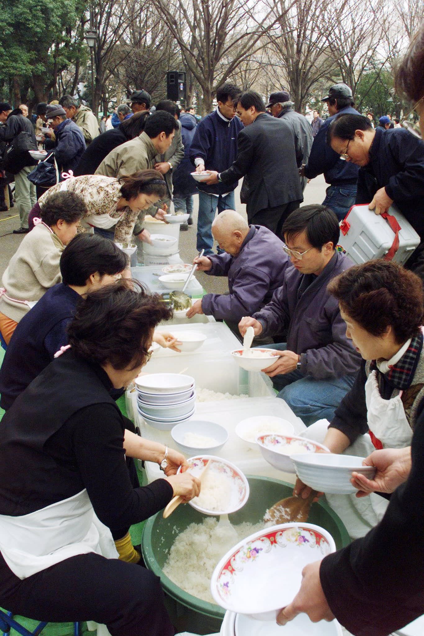 Church volunteers serve soup and rice to homeless and jobless people at a Tokyo park, March 30 1999.