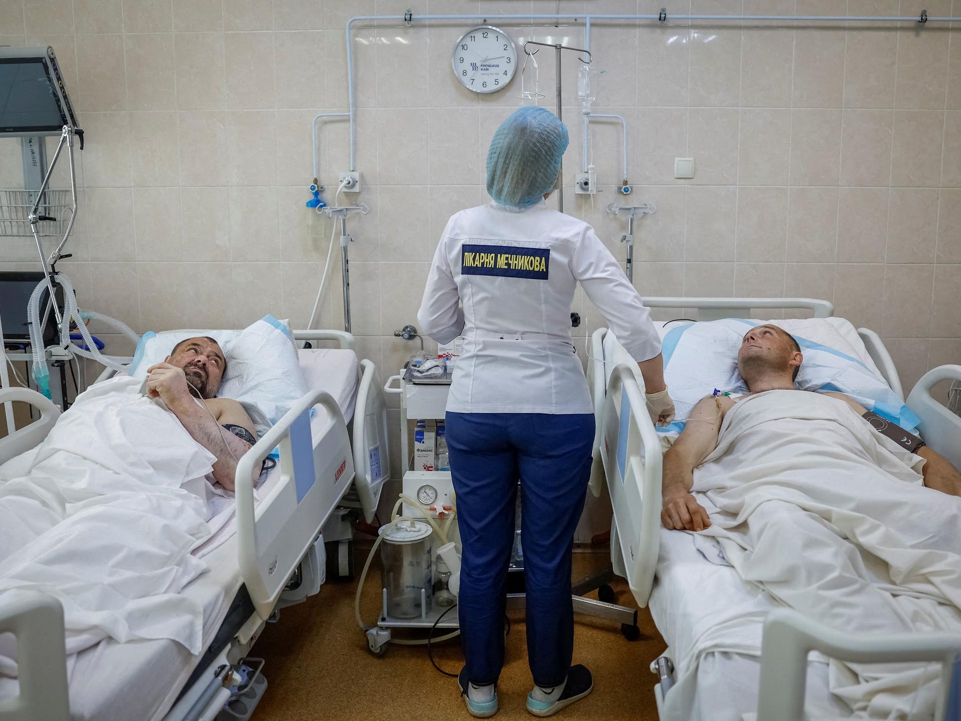A nurse at the Mechnikov Hospital treats service members Viktor Cherniy, 52, and Vitalii Yunatskyi, 40, who were wounded during fighting against Russian forces, in an intensive care unit, in Dnipro, Ukraine, on May 14, 2025.
