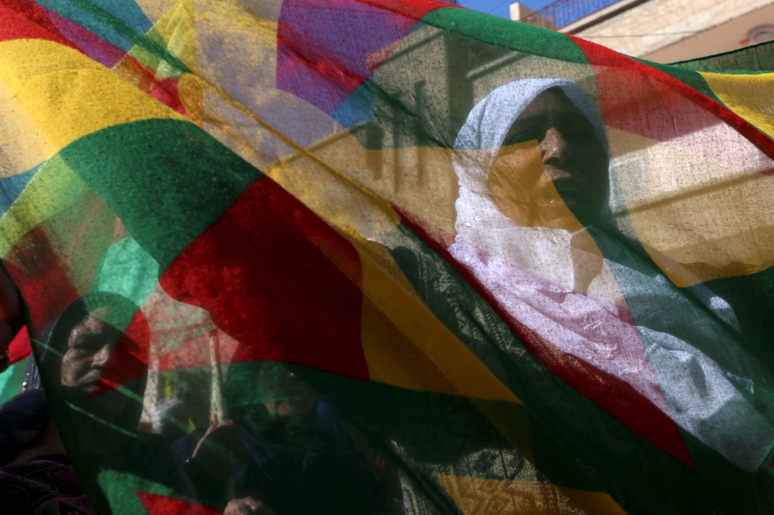 Kurdish women hold a flag as they march during a demonstration, in the northeast Syrian Kurdish city of Qamishli, on February 4, 2016.