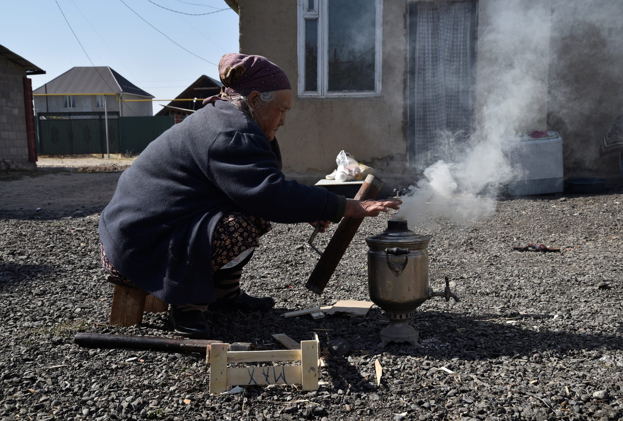 Rakya Kudaiberdiyeva, a 75-year-old pensioner, uses a samovar to boil water outside her family's rented house, in Bishkek, Kyrgyzstan, on October 13, 2020.