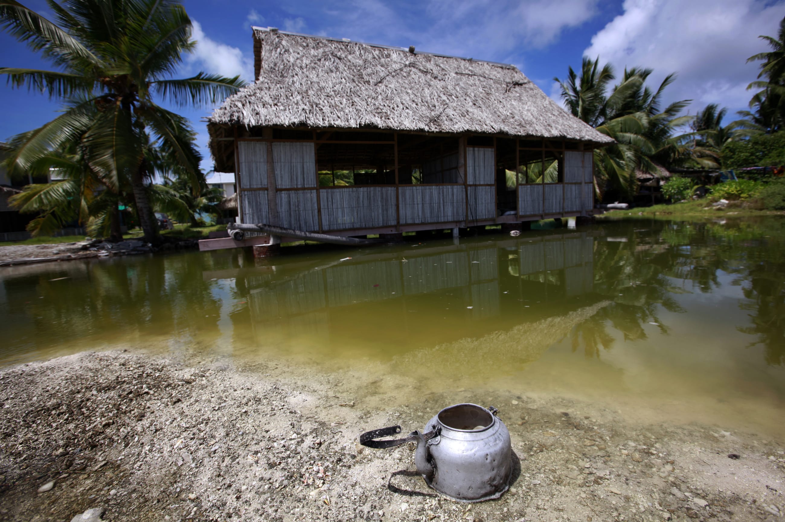 An abandoned house that is affected by seawater during high-tides stands next to a small lagoon, near the village of Tangintebu, on South Tarawa, in the central Pacific island nation of Kiribati, on May 25, 2013.