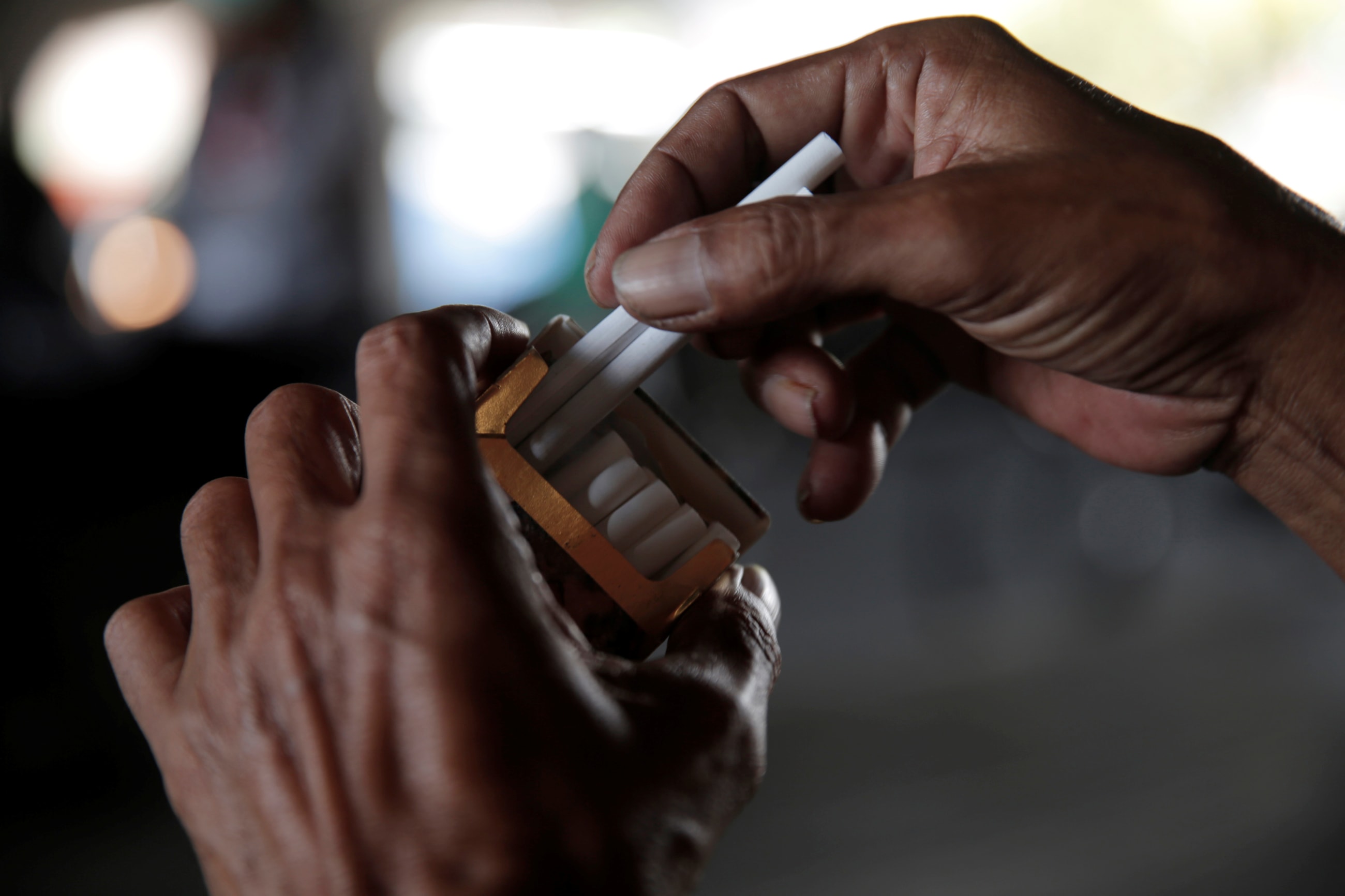 A street vendor holds cigarettes as he serves a consumer, in Jakarta, Indonesia, on March 15, 2017.