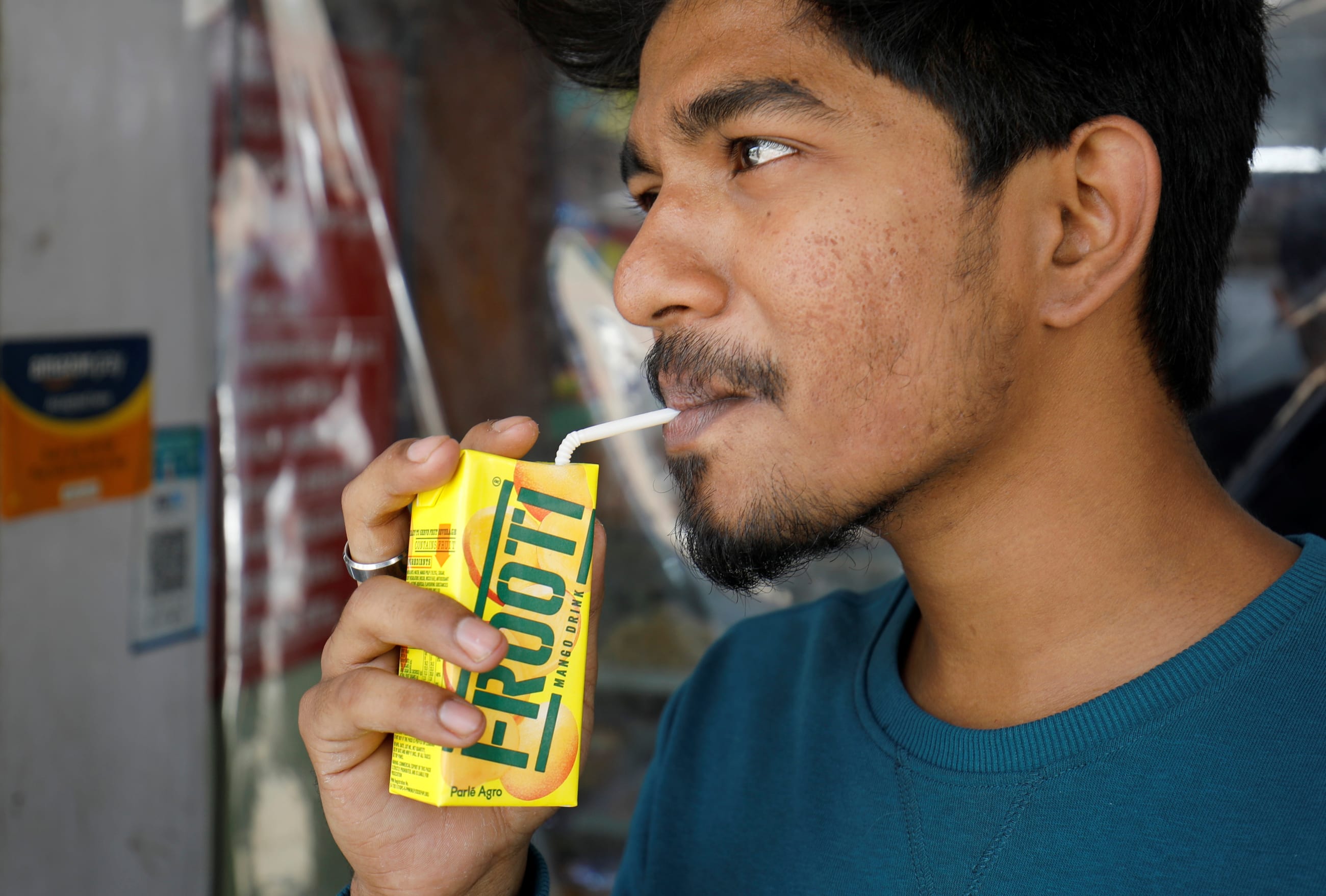 A man consumes Parle Agro's Frooti mango flavored drink outside a shop, in Ahmedabad, India, on April 8, 2022.