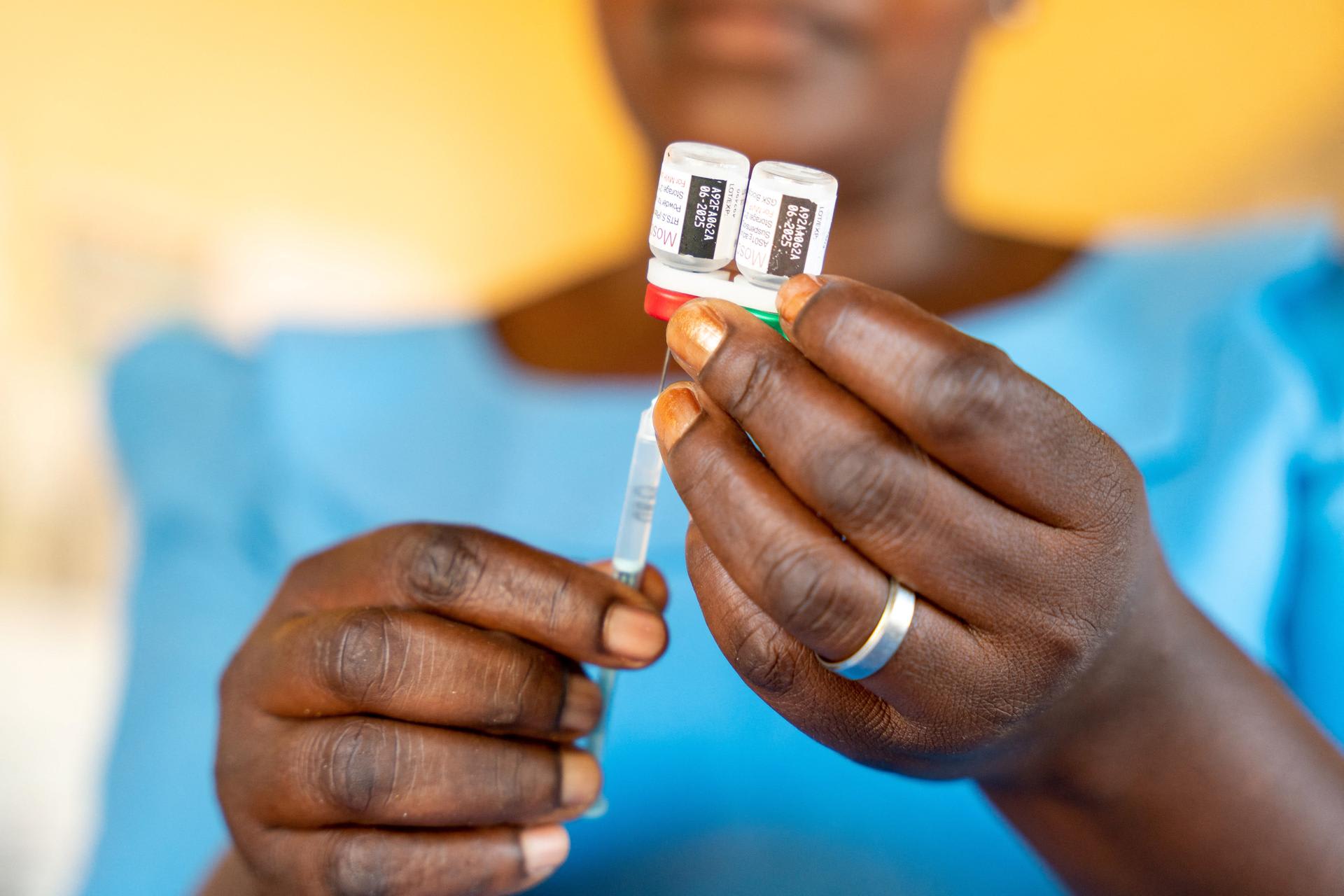 A worker holds a malaria vaccine vial to administer to a child, at Chileka Health Center, in Lilongwe, Malawi