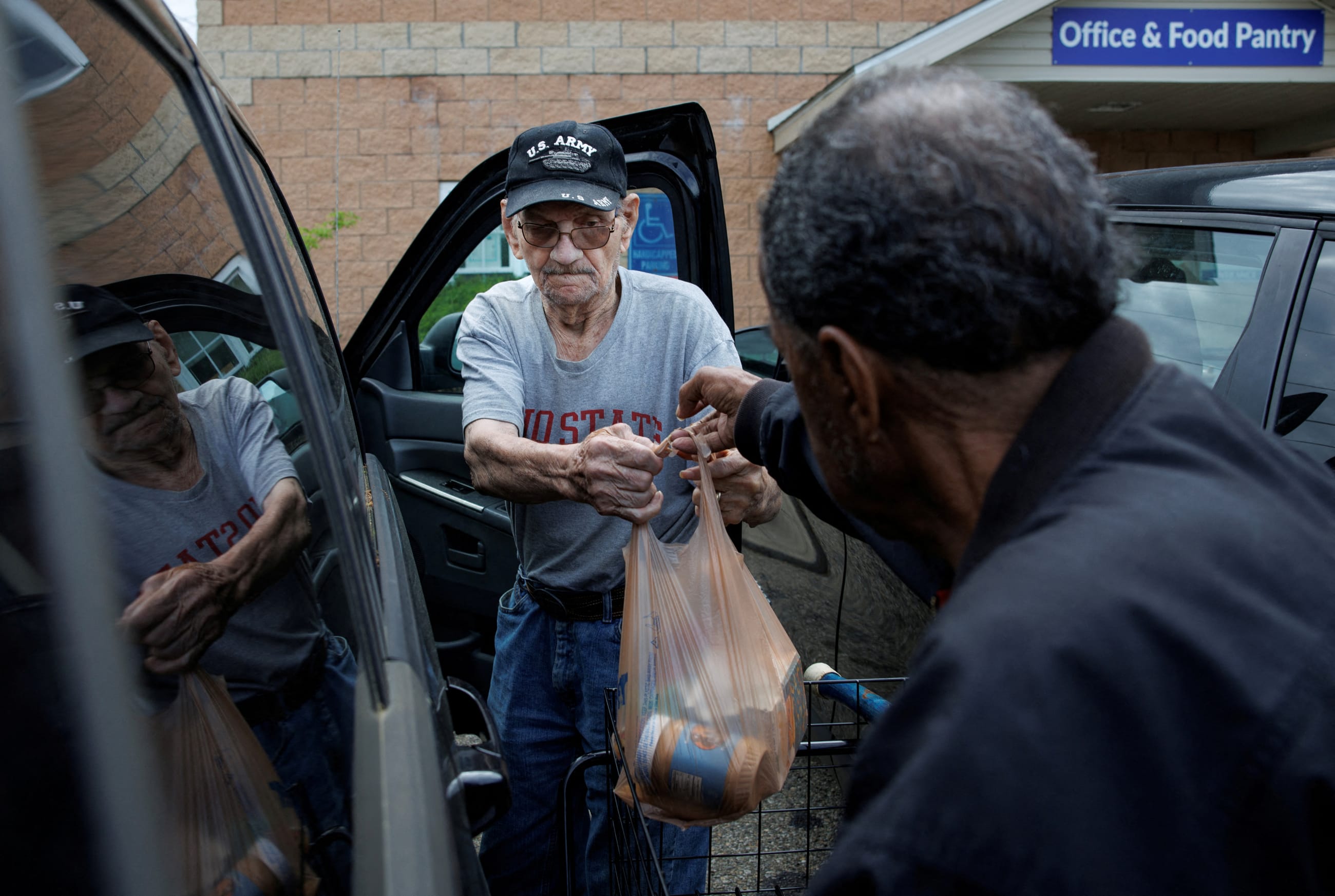 Volunteer Walter Rogers, 83, helps Merrill Hancock, 87, load the groceries he received from the Eastside Community Ministry pantry which is supplied by the Mid-Ohio Food Collective, in Zanesville, Ohio, on May 12, 2025.