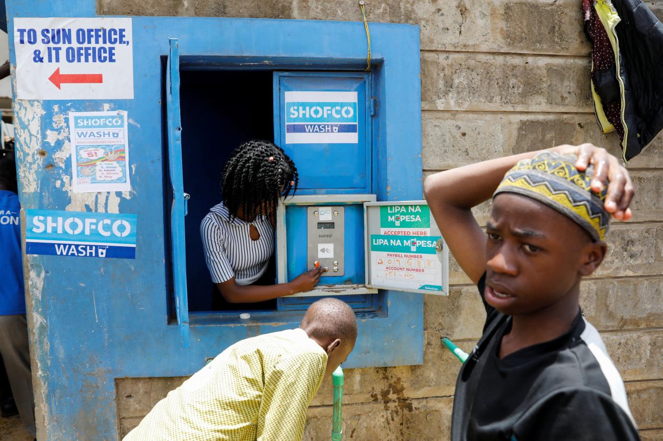 An employee of the community organization, Shining Hope for Communities, activates a water selling machine at a in the Kibera slum, in Nairobi, Kenya, on March 18, 2020.