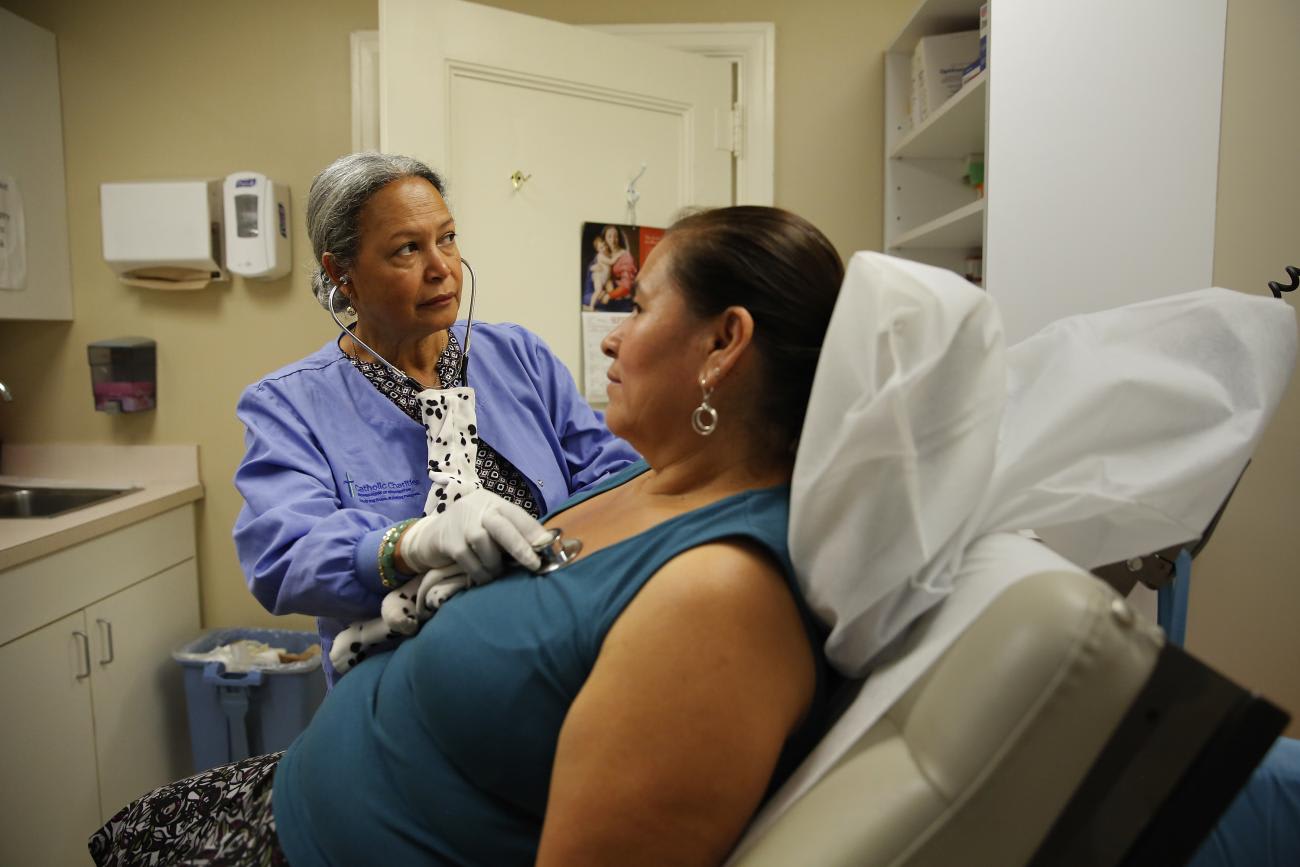 A nurse listens to a client's chest at the Spanish Catholic Center agency.
