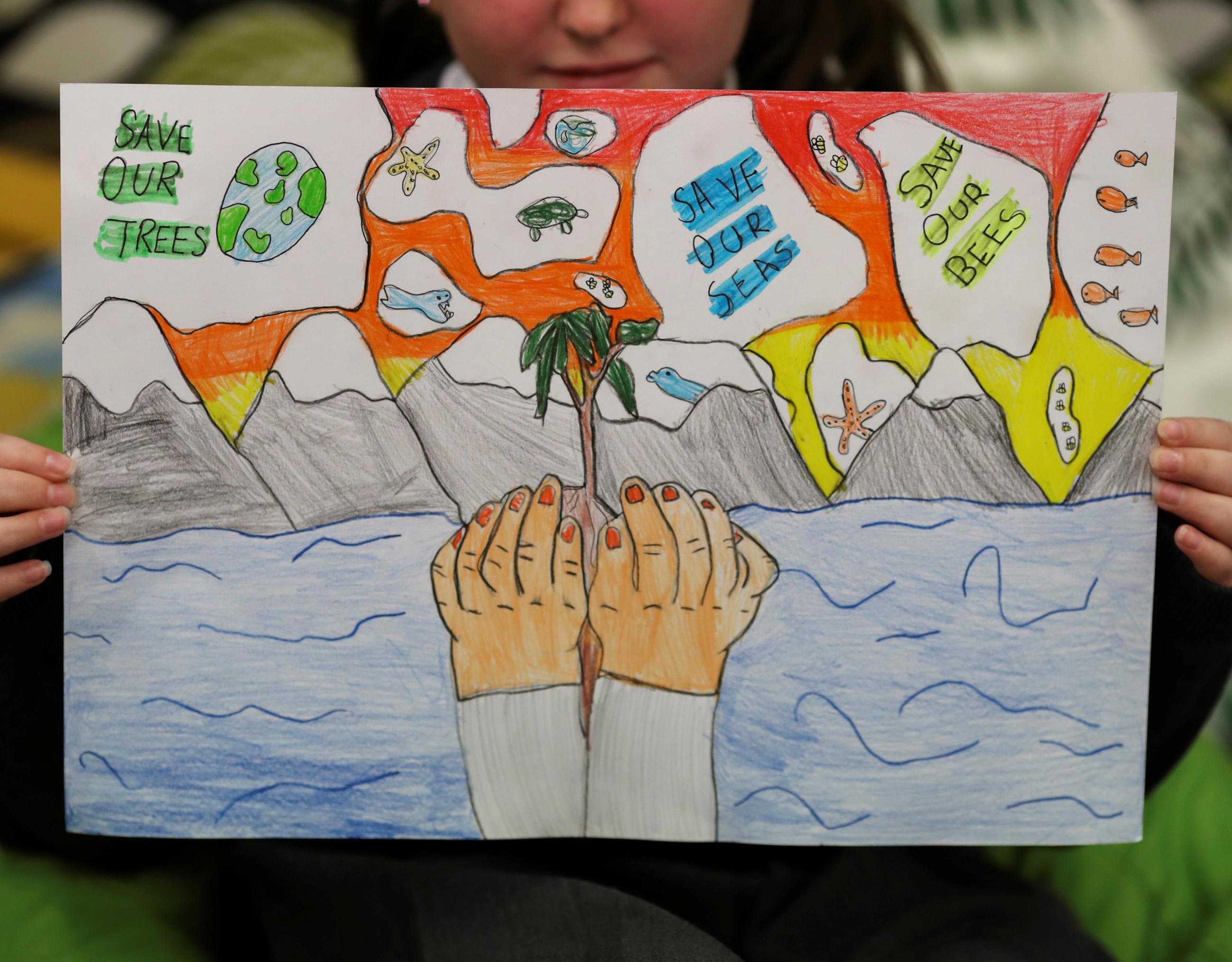 A student holds a poster at St. Convals Primary Glasgow while learning about climate change ahead of COP26, in Glasgow, Scotland, on October 19, 2021.