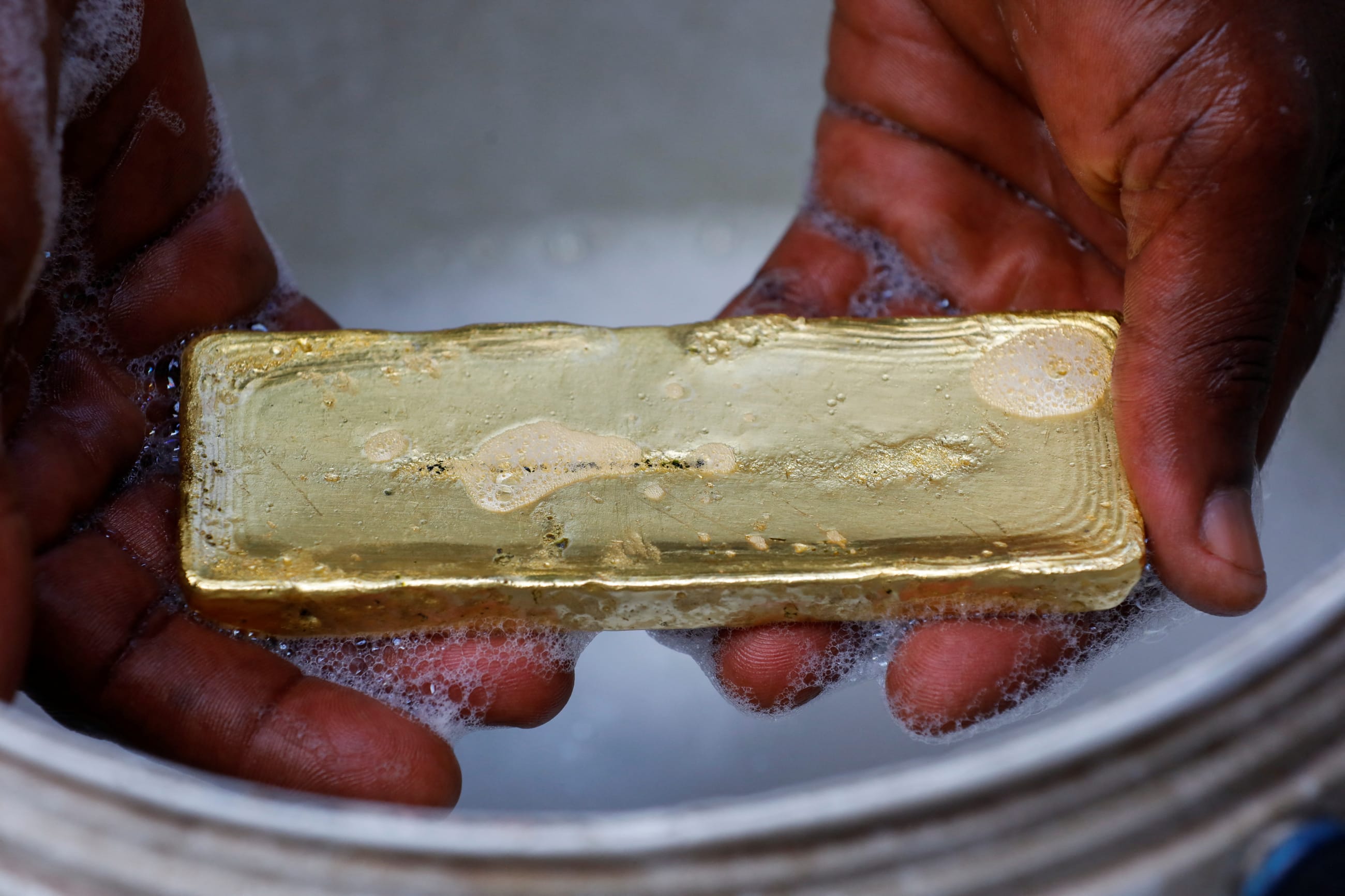 A worker washes off excess impurities during a gold smelting process at a facility in Accra, Ghana, on August 22, 2024.