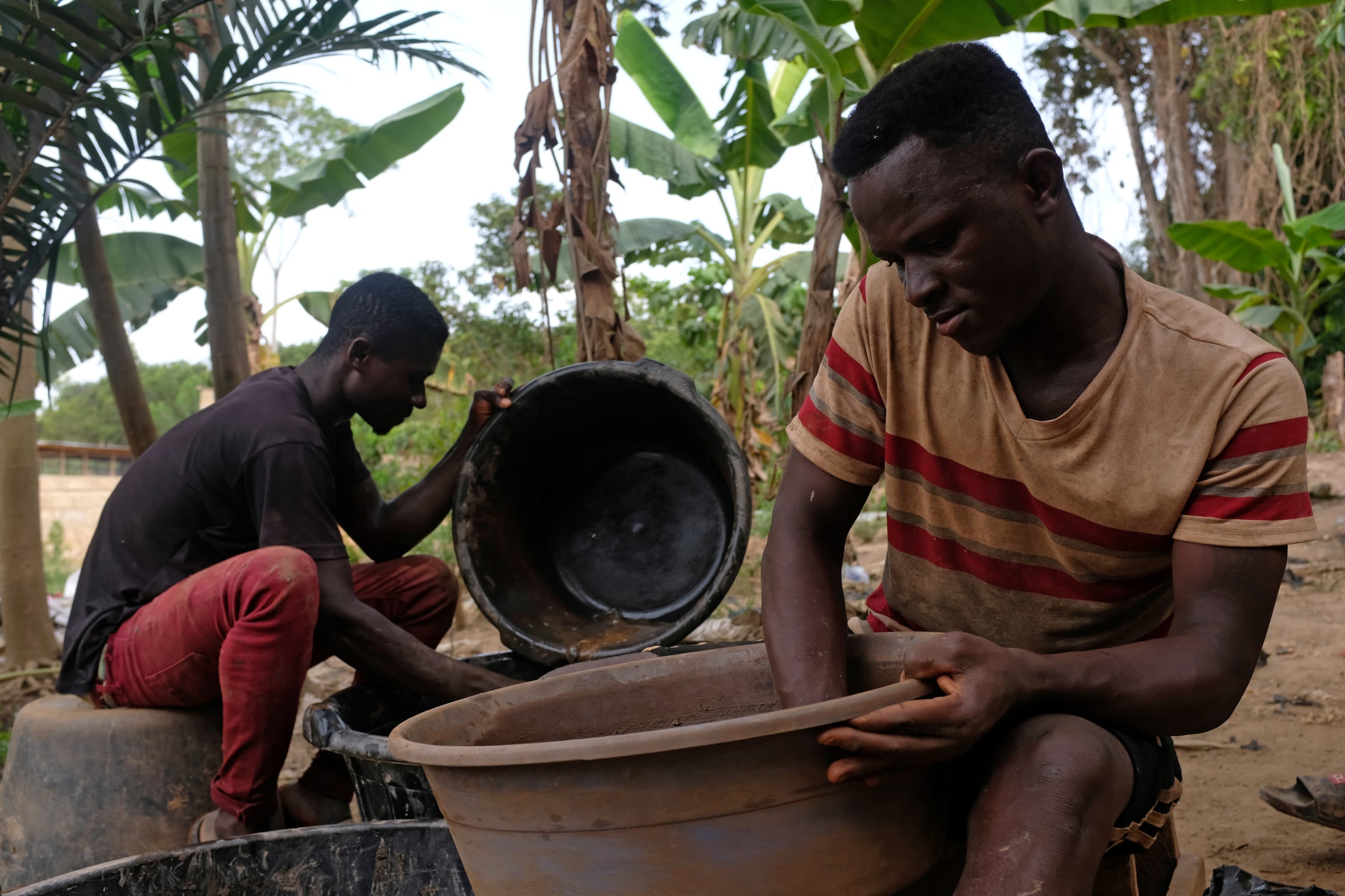 Informal gold miners mix mercury with water and dirt in plastic tubs to extract gold, at a site in Bawdie, Ghana, on April 5, 2019.