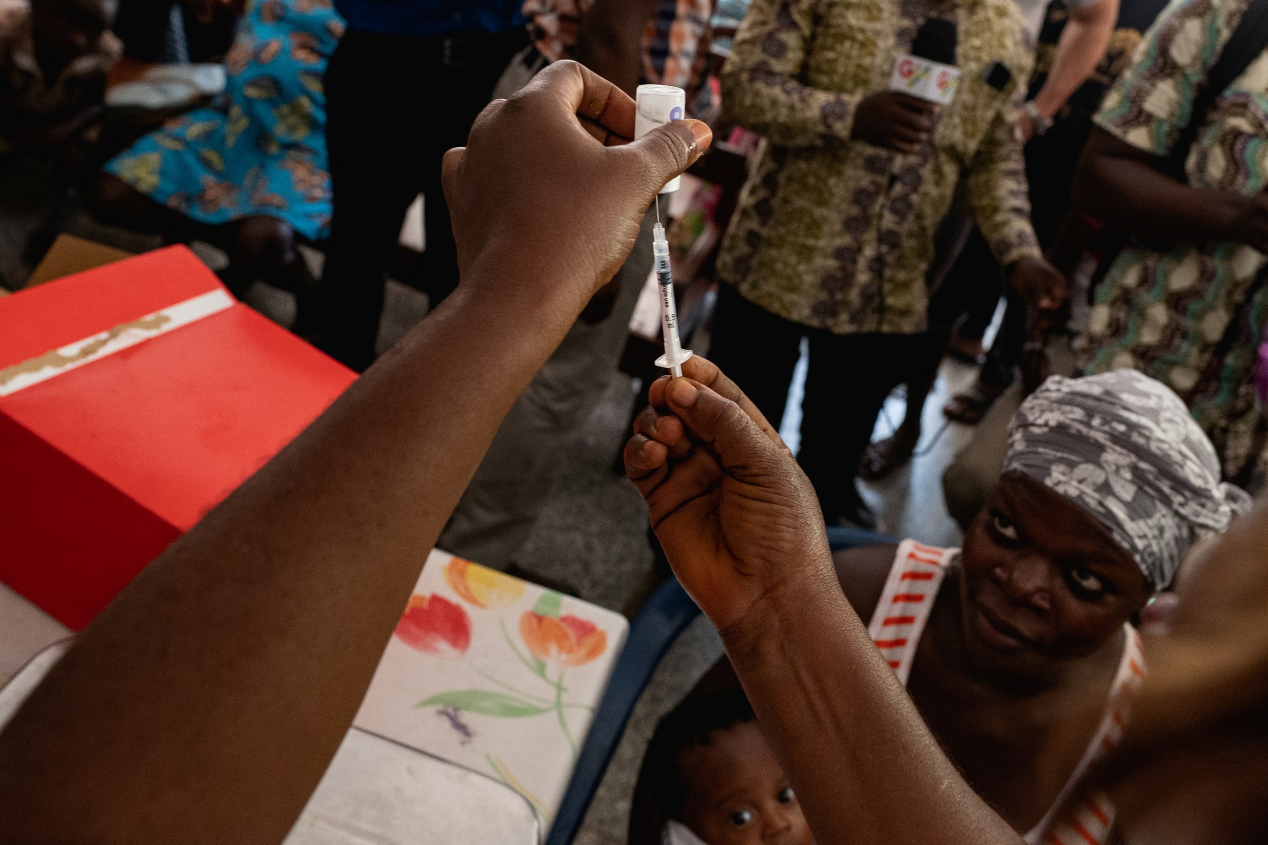 A nurse holds a syringe as patients wait for vaccinations after Zipline drones, supported by Gavi and the UPS Foundation, cut the time taken to deliver lifesaving medical supplies from hours to minutes, in Ghana, on April 23, 2019.