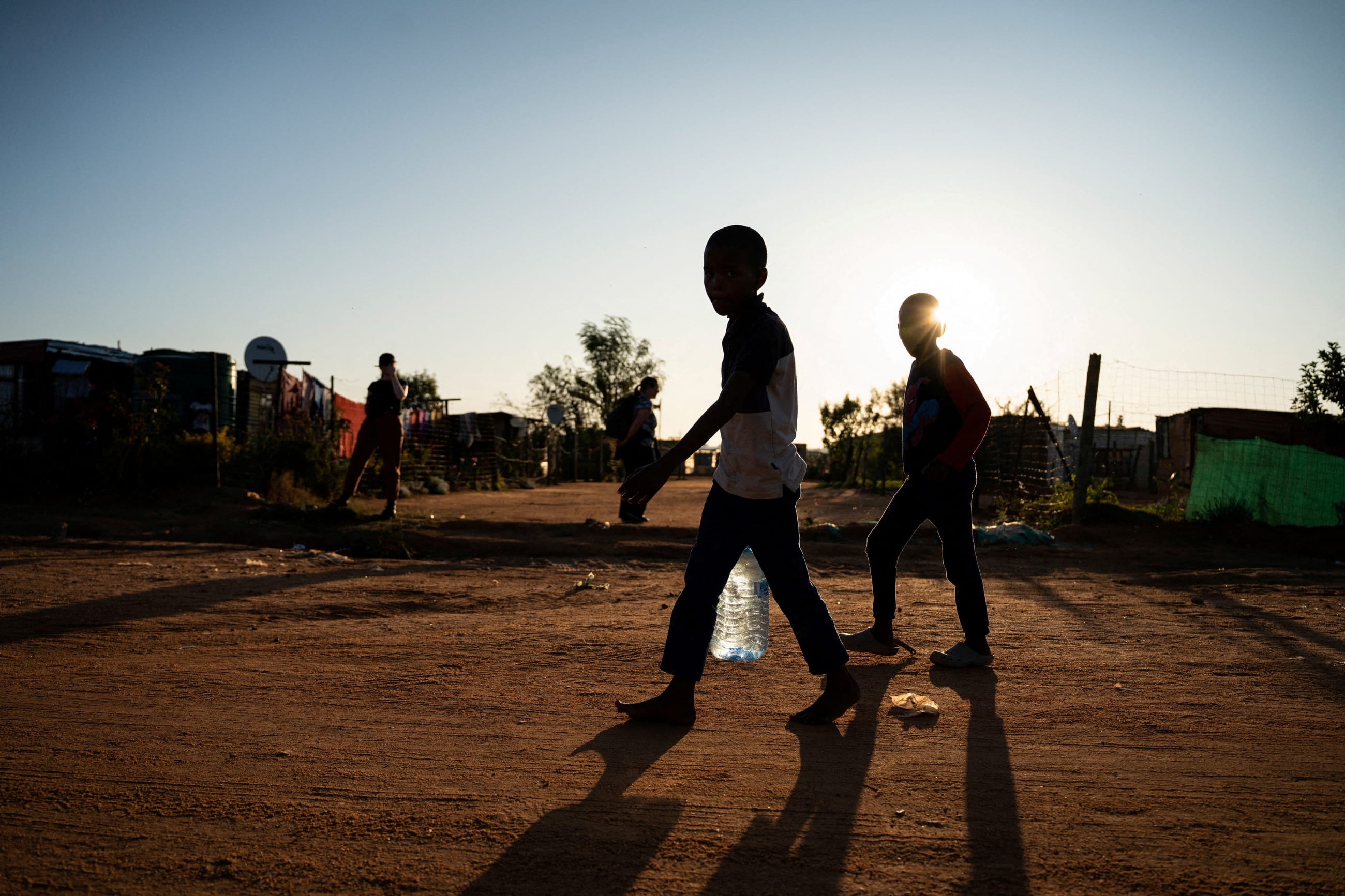 Young residents carry water home after filling up a bottle at a community filling station in the informal settlement of Kanana, in Hammanskraal, South Africa, on May 24, 2023.
