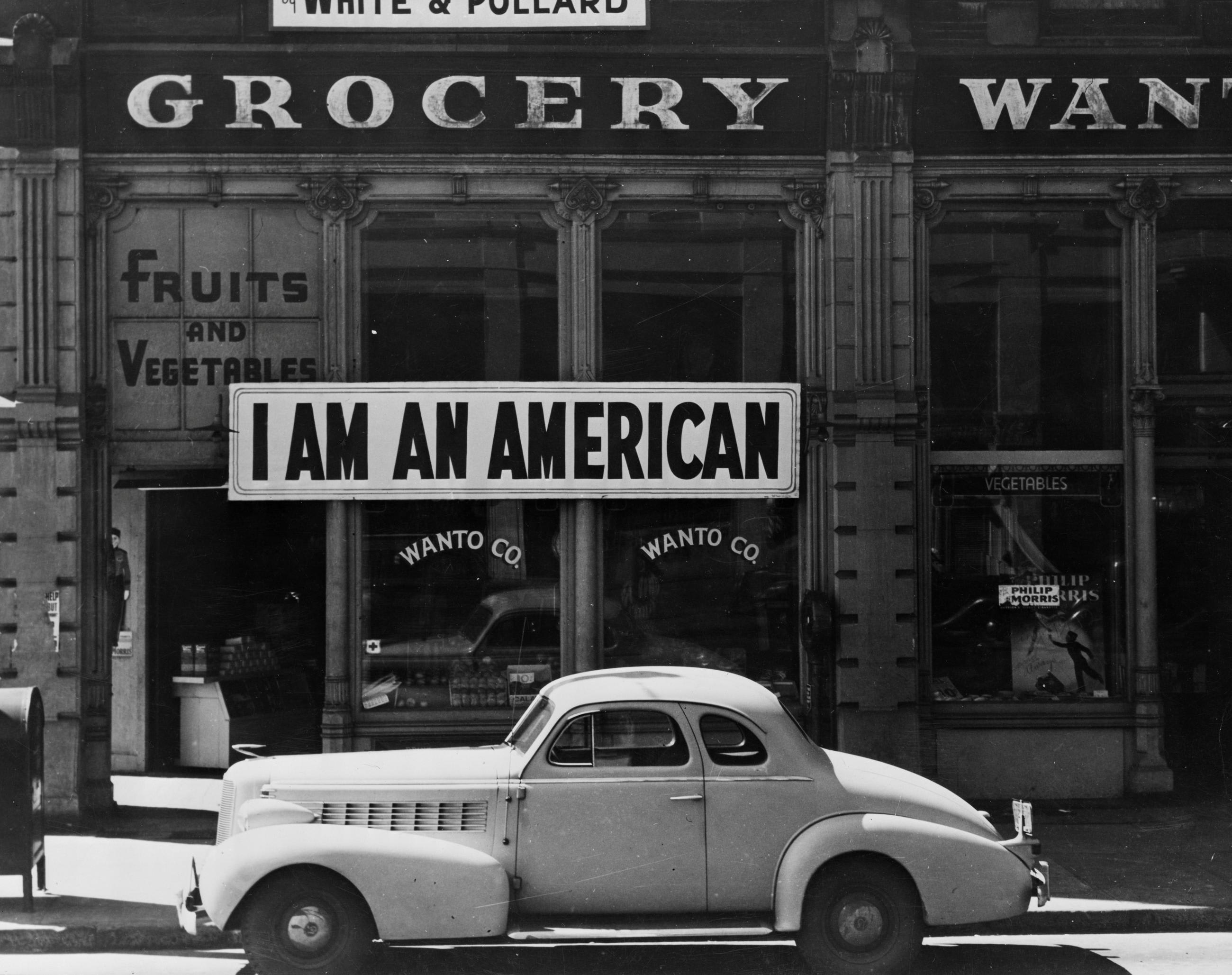A large sign reading "I am an American" is placed in the window of a store following orders to persons of Japanese descent to evacuate from certain West Coast areas in Oakland, California in 1942.