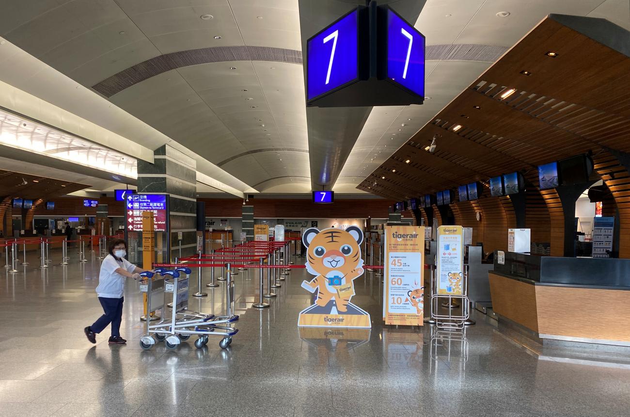 A staff member wearing a face mask following the coronavirus disease (COVID-19) outbreak pushes trolleys past empty counters at Taipei's Taoyuan International Airport, in Taiwan July 17, 2020