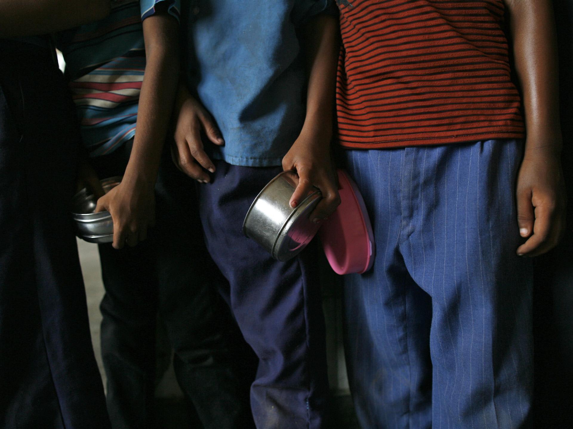 School boys carry tiffin boxes as they wait to receive their free midday meal, distributed by a government-run primary school, in New Delhi, India, on July 19, 2013.