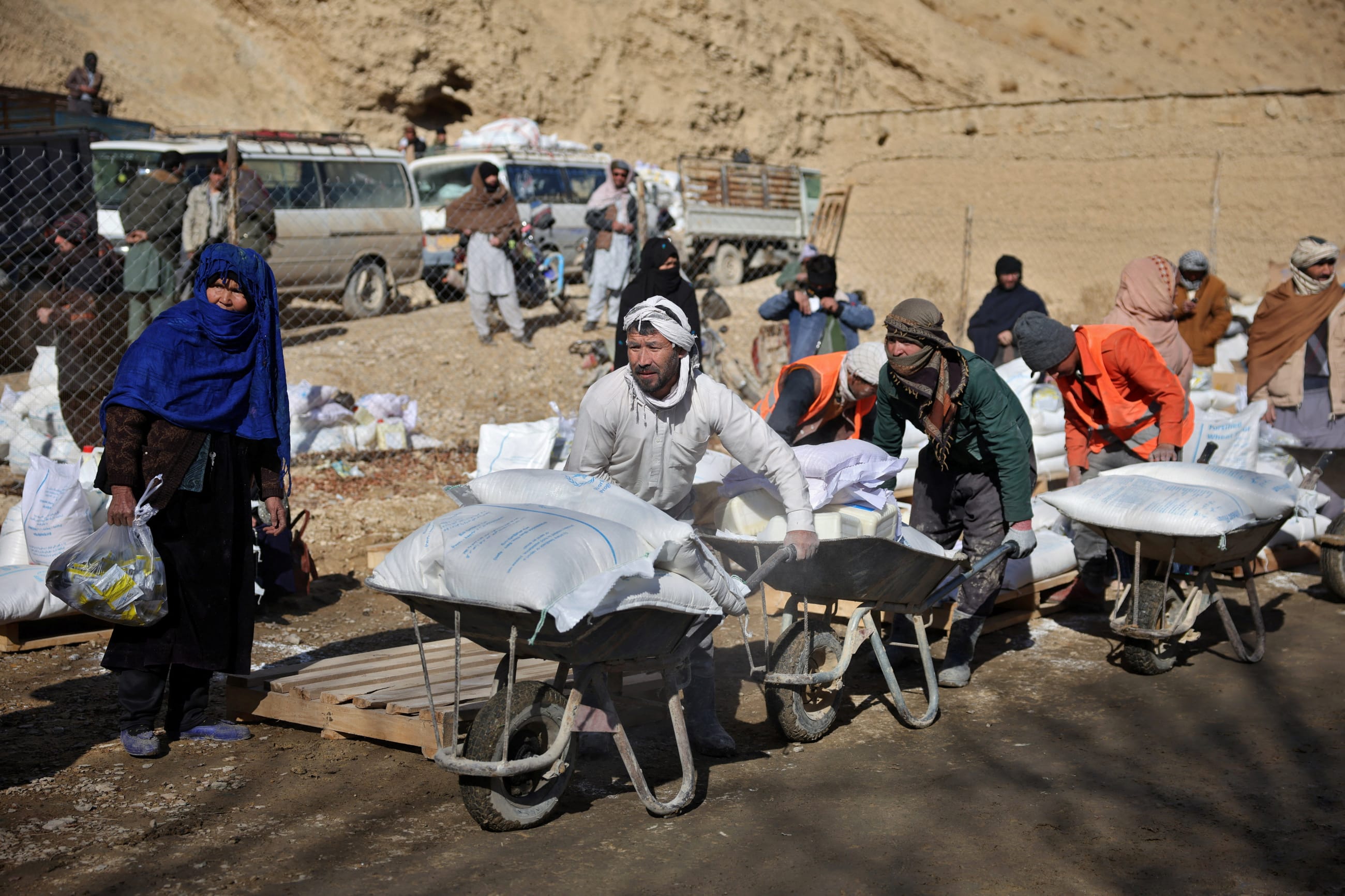 Laborers move sacks of flour on pushcarts at a World Food Program distribution center, in Yakawlang, Bamyan province, Afghanistan, on January 1, 2026.