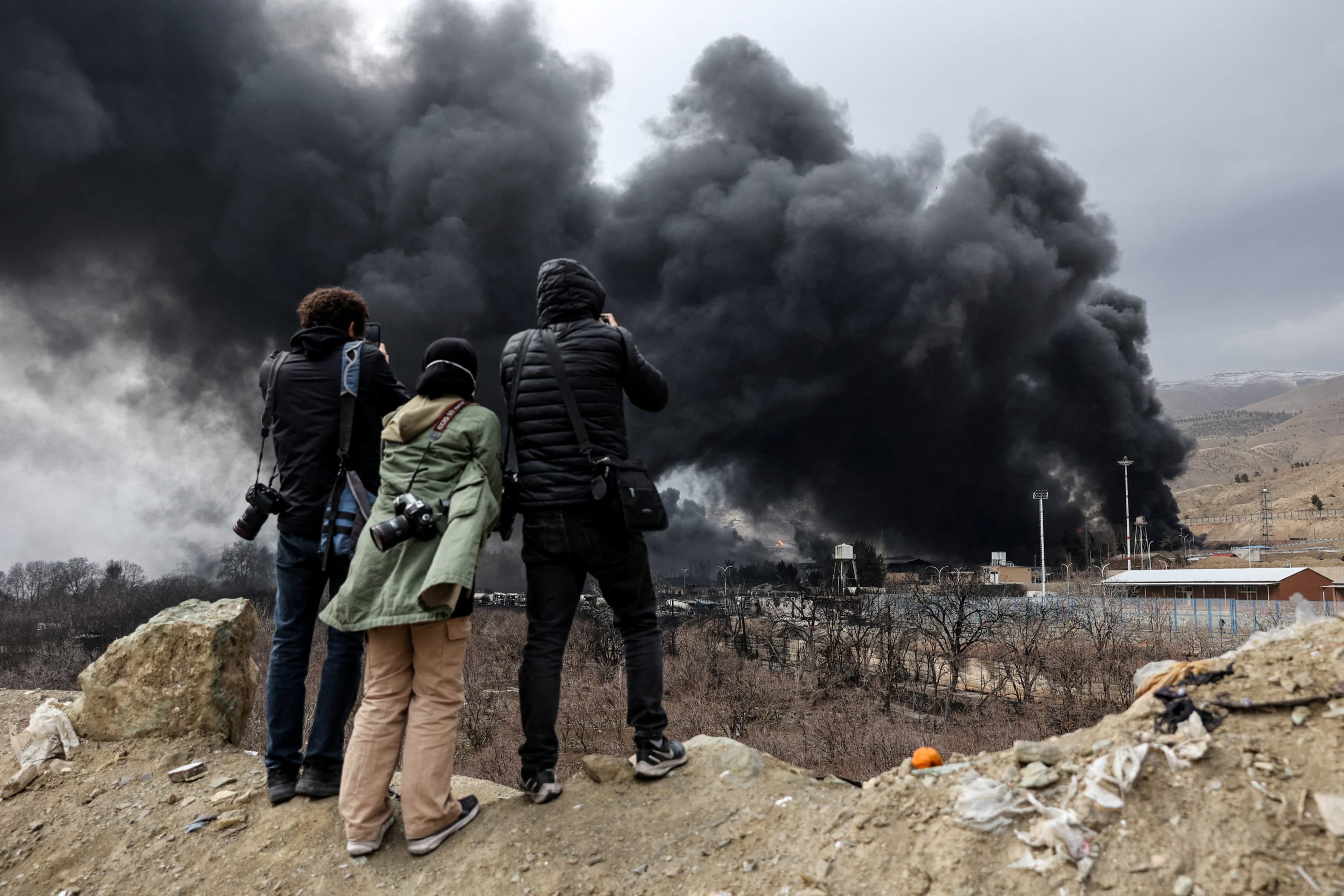 People record smoke rising after a reported strike on Shahran fuel tanks, in Tehran, Iran, on March 8, 2026.