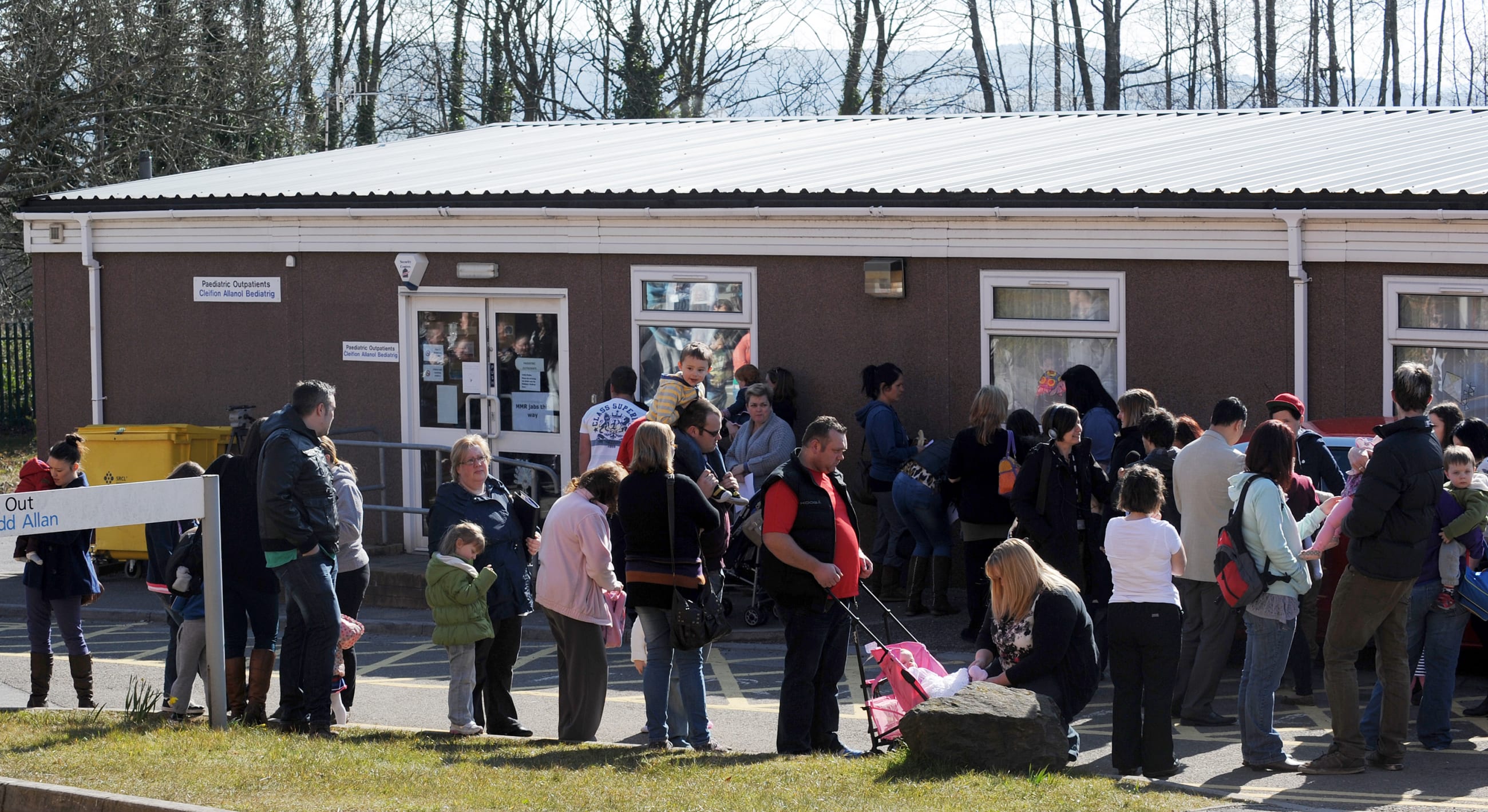 Parents and children queue outside the pediatric outpatient department at Morriston Hospital in Swansea, south Wales, on April 6, 2013.