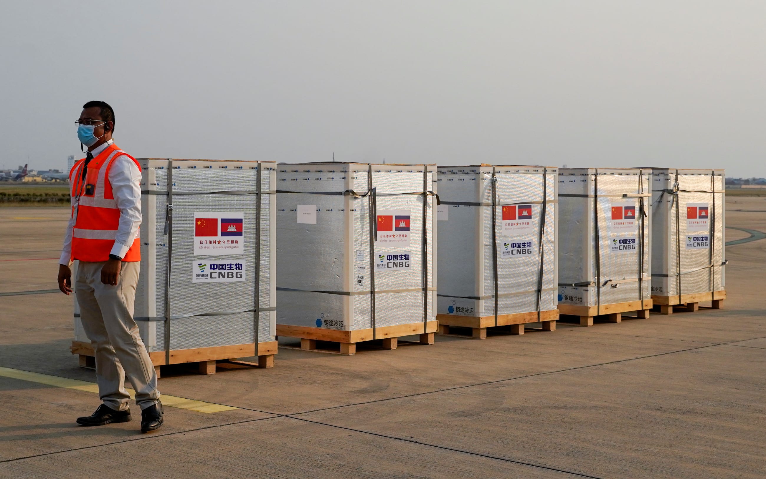 A worker stands next to the shipment of 600,000 doses of the COVID-19 vaccines donated by China, at the Phnom Penh International Airport, in Phnom Penh, Cambodia, on February 7, 2021.