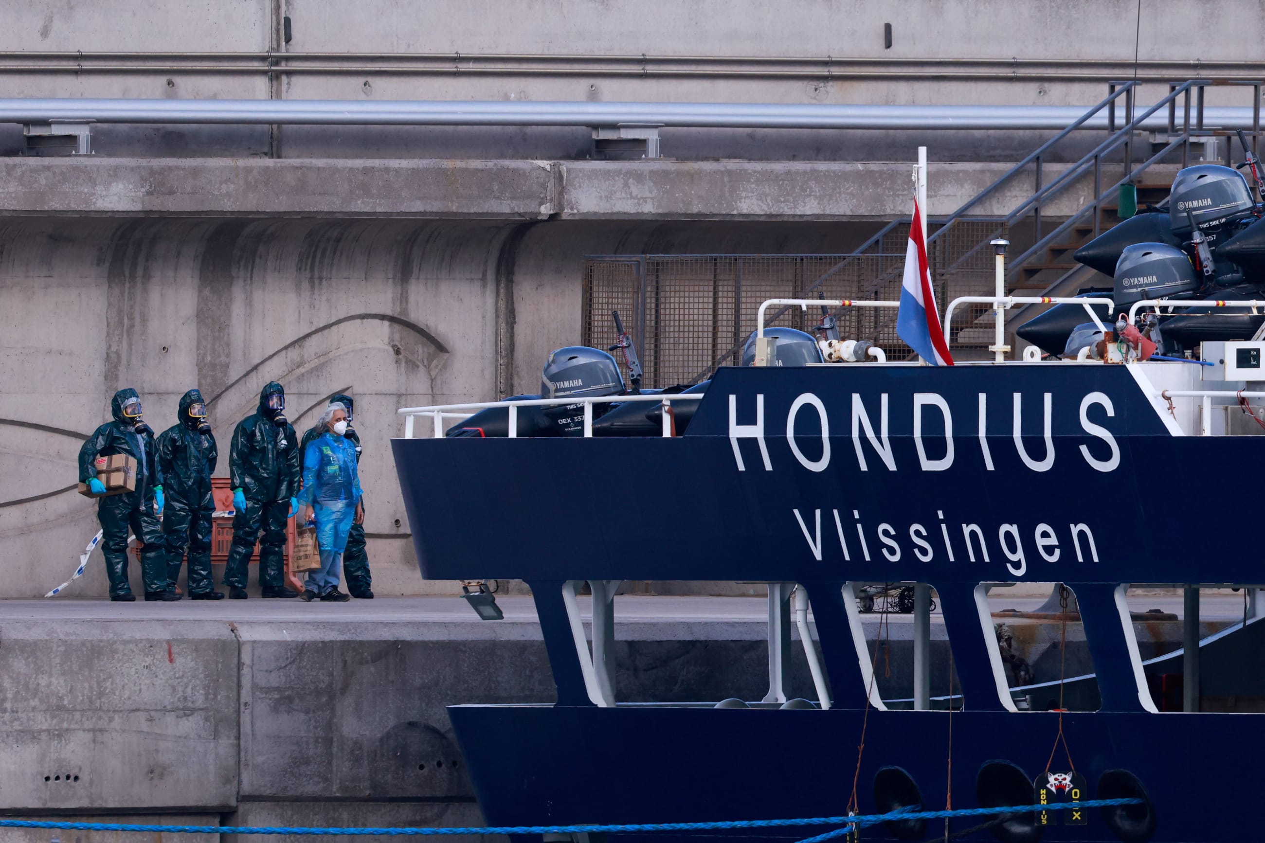 People in hazmat suits and personal protective equipment stand near the cruise ship MV Hondius, affected by a hantavirus outbreak, after it docked at the port of Granadilla de Abona, in Tenerife, Spain, on May 11, 2026.
