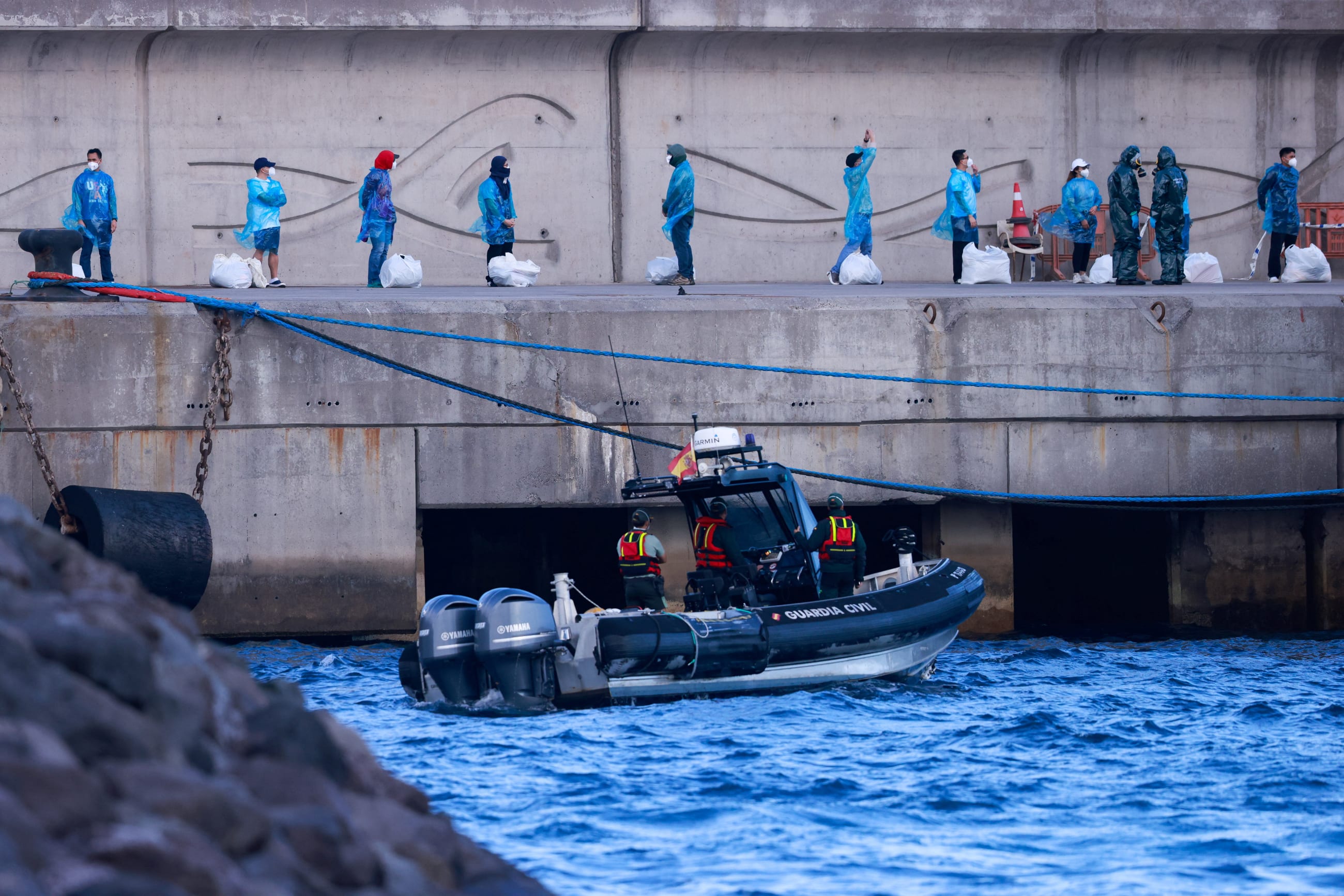 Tourists wait at the dock after disembarking from the cruise ship MV Hondius, affected by a hantavirus outbreak, at the port of Granadilla de Abona, Tenerife, Spain, on May 11, 2026