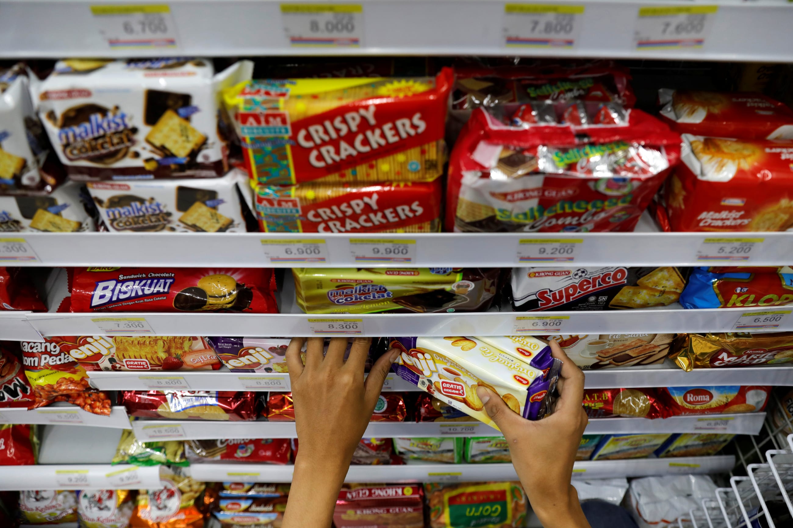 A shopkeeper arranges snacks to sell at a mini market, in Jakarta, Indonesia, on February 15, 2019.
