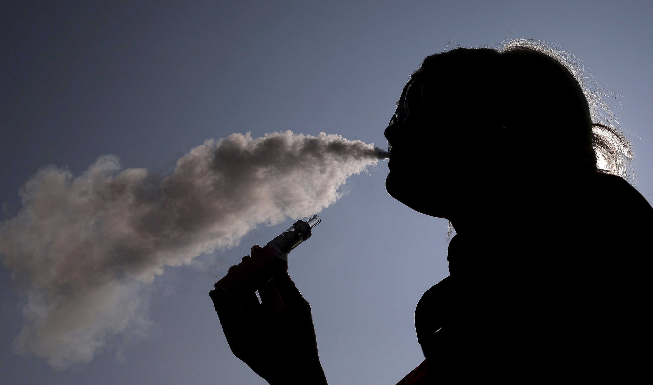 A woman exhales vapour from an e-cigarette outside the offices of British e-cigarette manufacturer Totally Wicked in Blackburn, England, on March 19, 2015.