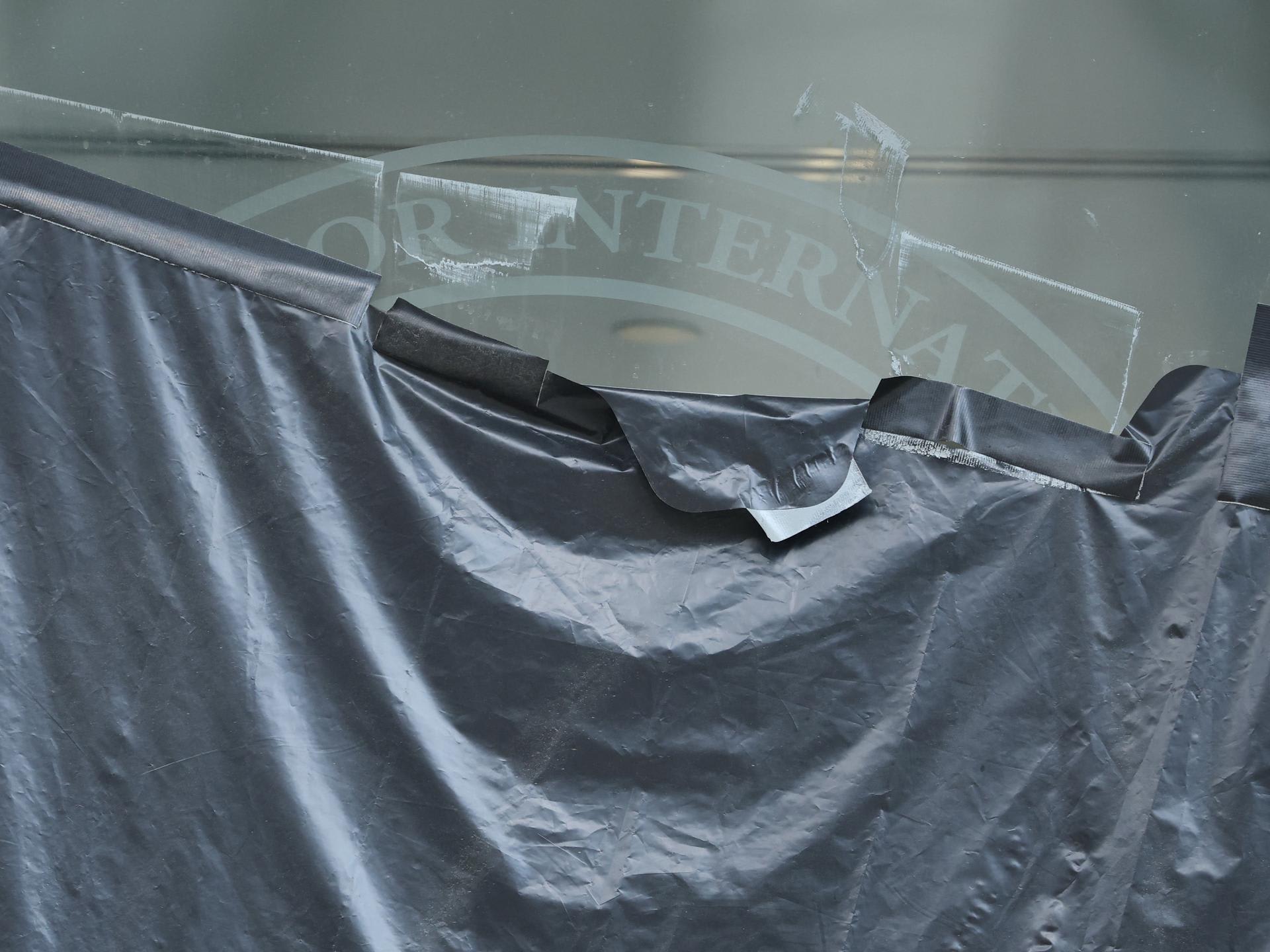 Plastic peels back to reveal the covered logo on the windows of the shuttered offices of the U.S. Agency for International Development, in Washington, DC, on July 22, 2025.