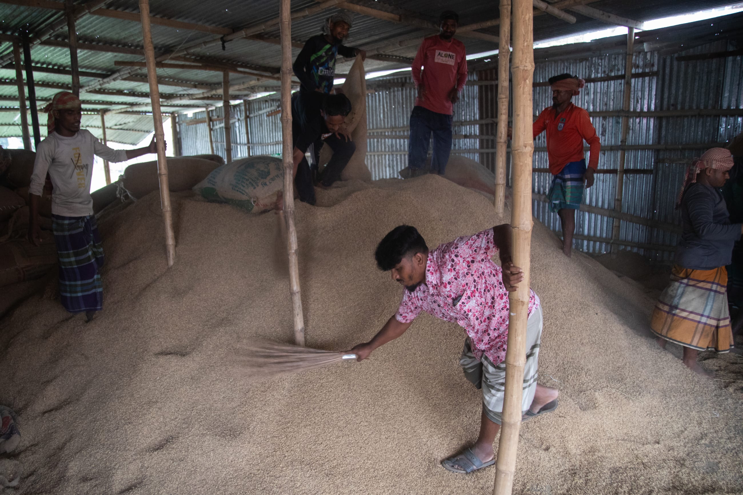 Workers spread out wet harvests to dry at a grain storage facility, in Kishoreganj, Bangladesh, on May 21, 2026.